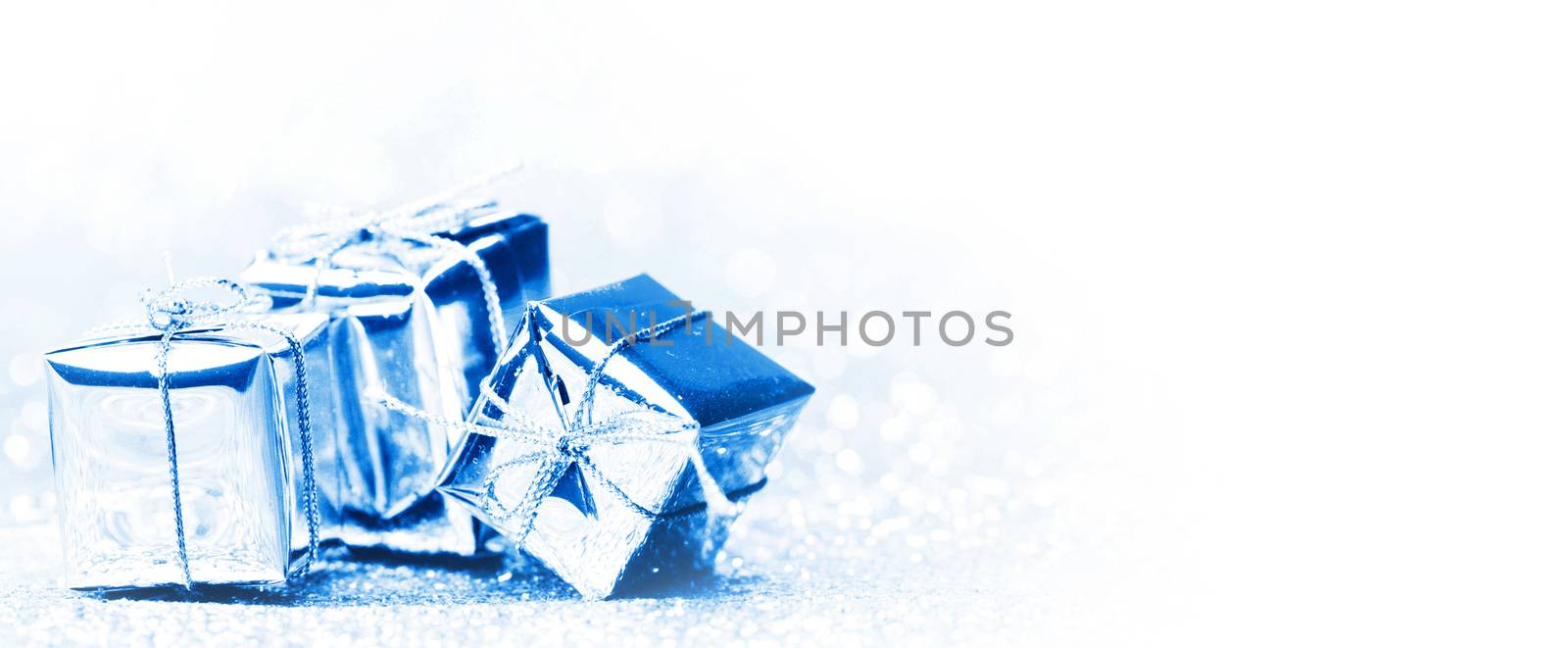 Silver holiday gifts on silver glitter background