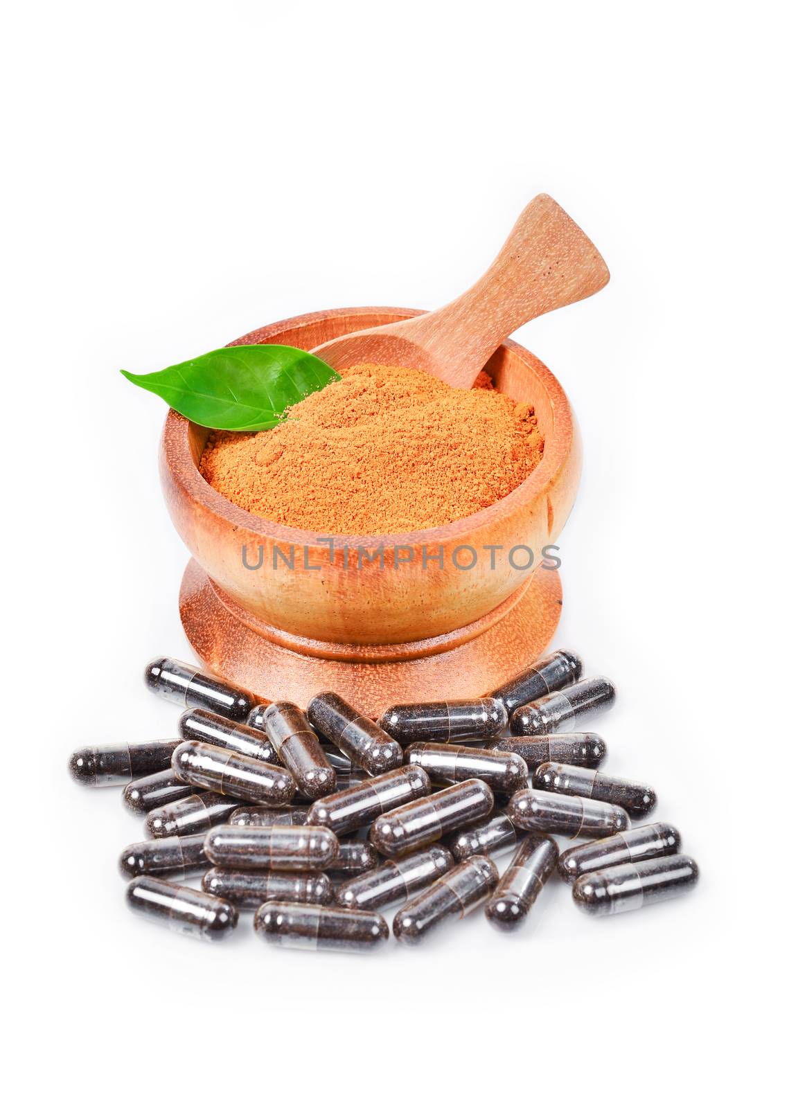 Natural medicine capsule pill with black herb, and wooden mortar on white background for alternative medical concept.