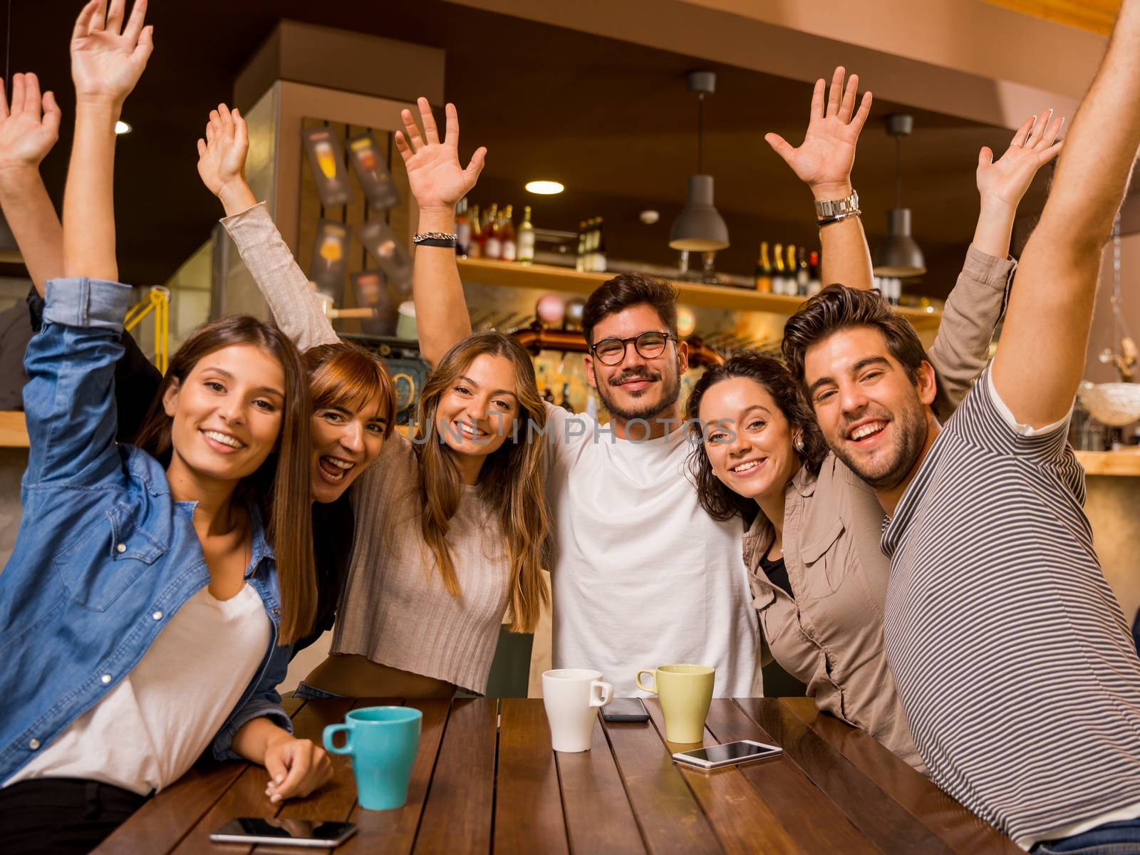 Group of friends raising hands and looking to the camera 