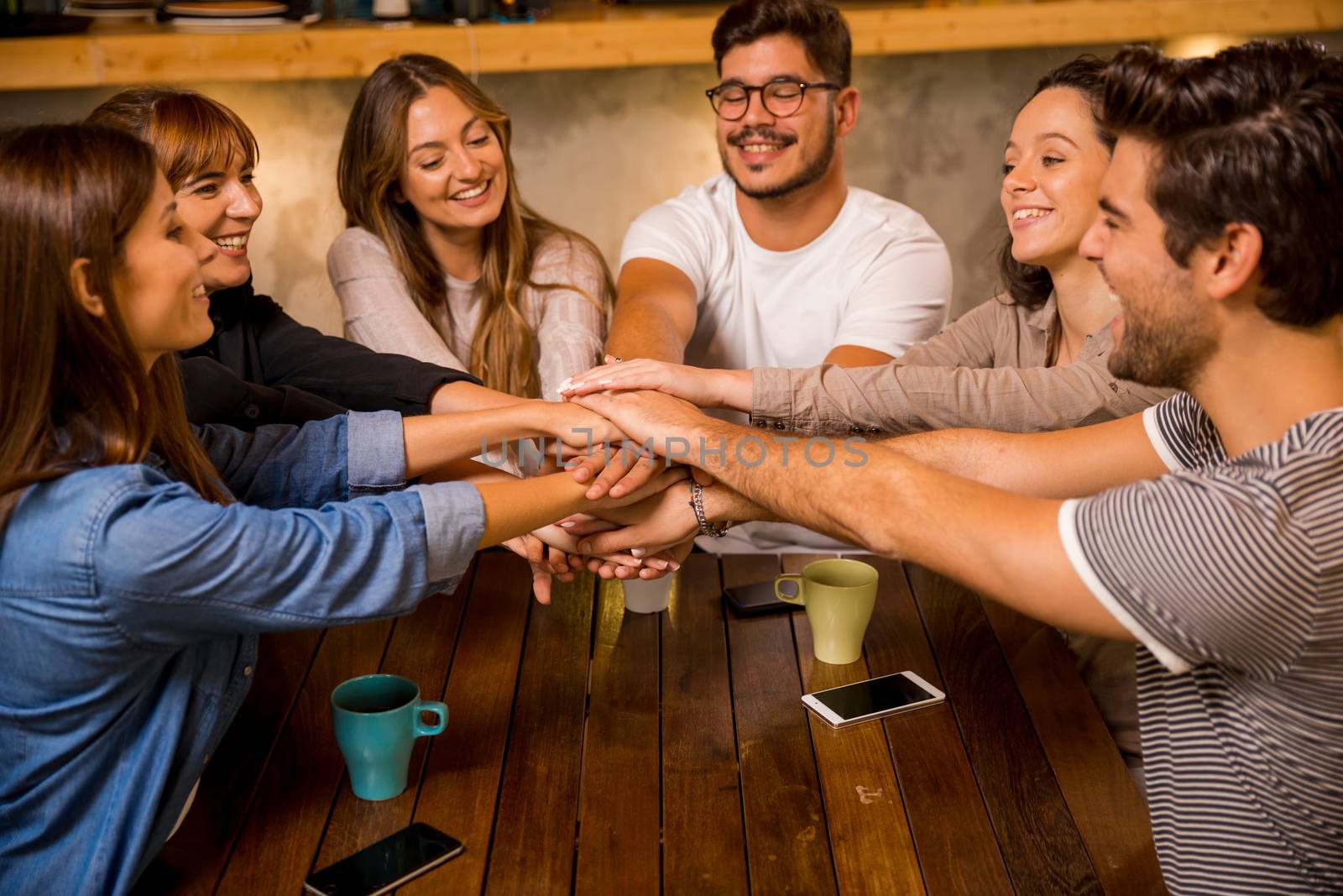 Group of friends joining their hands together at the cafe 