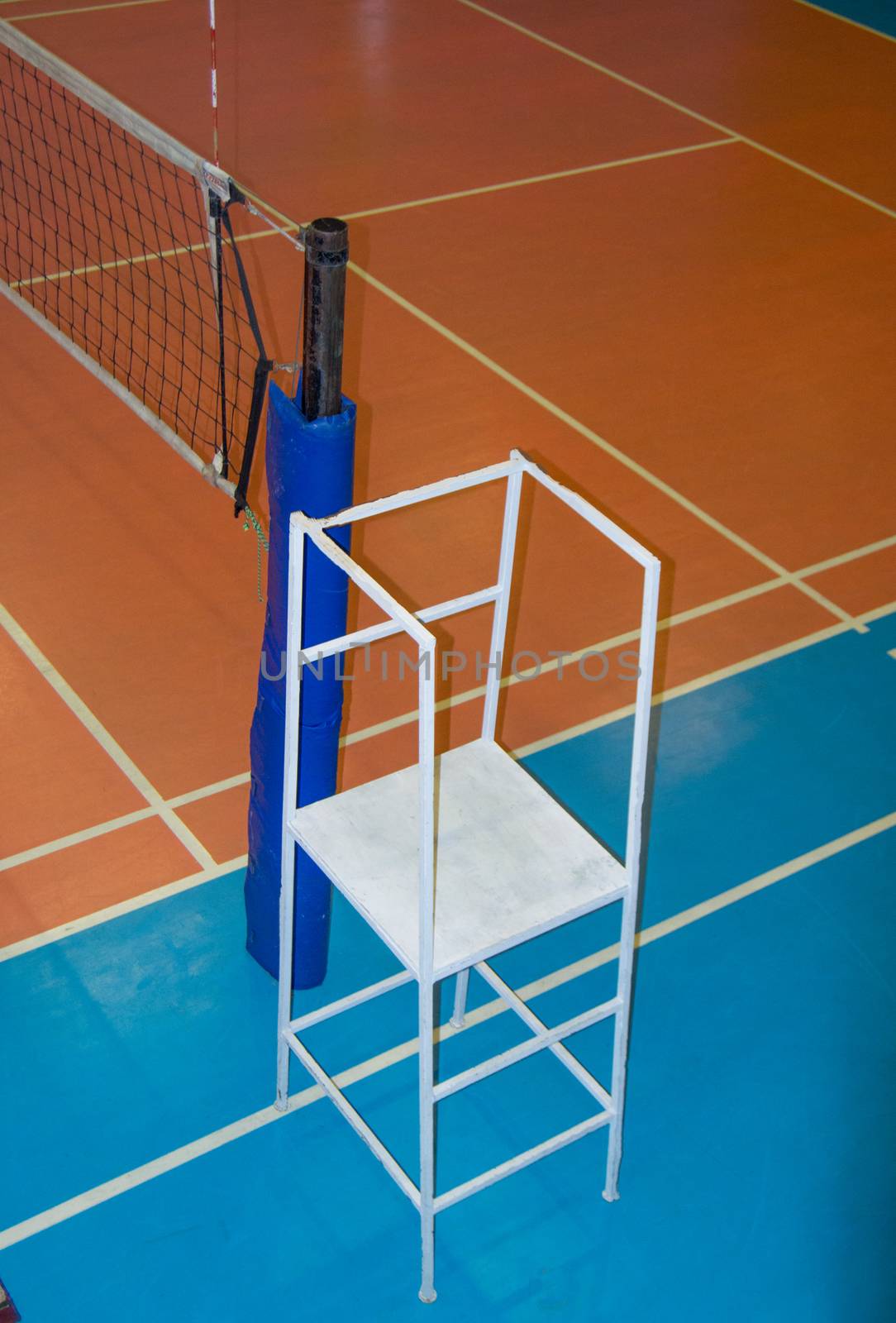 Empty sports hall with a stretched volleyball net and a tower for the judge.