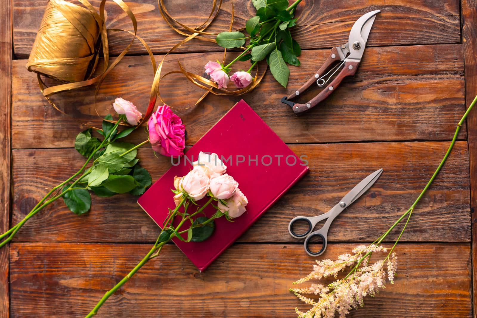 The workplace of the florist to work. Top view. Making floral decorations. Flowers on a old wooden table. Tools and accessories florists need for making up a bouquet. by rdv27