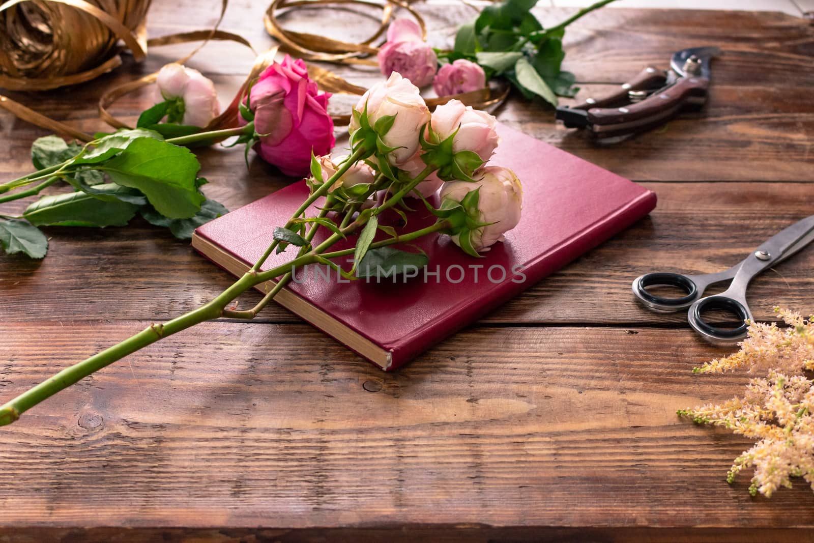 The workplace of the florist to work. Side view. Making floral decorations. Flowers on a old wooden table. Tools and accessories florists need for making up a bouquet. by rdv27