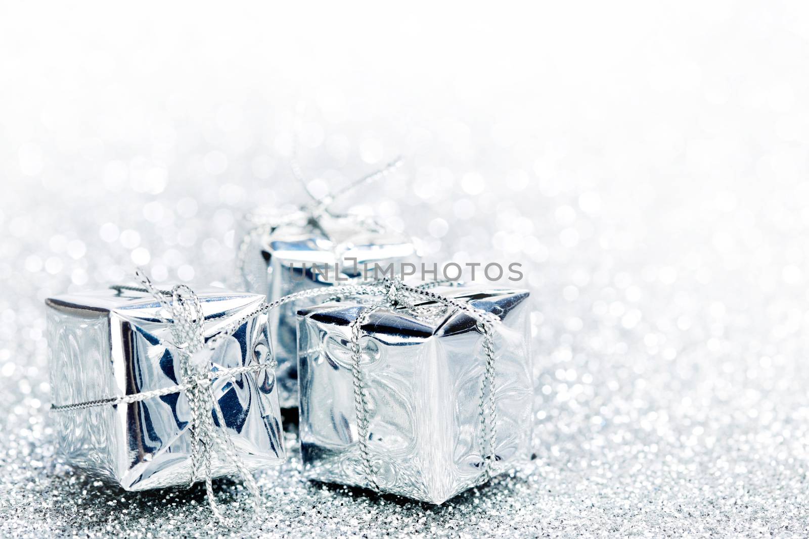 Decorative silver boxes with holiday gifts on shiny glitter background