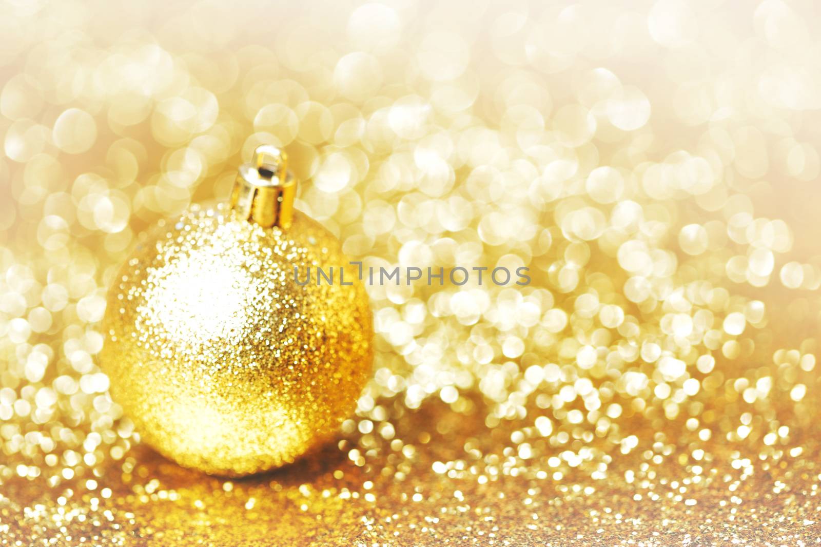 Golden christmas ball on shining glitter background close-up