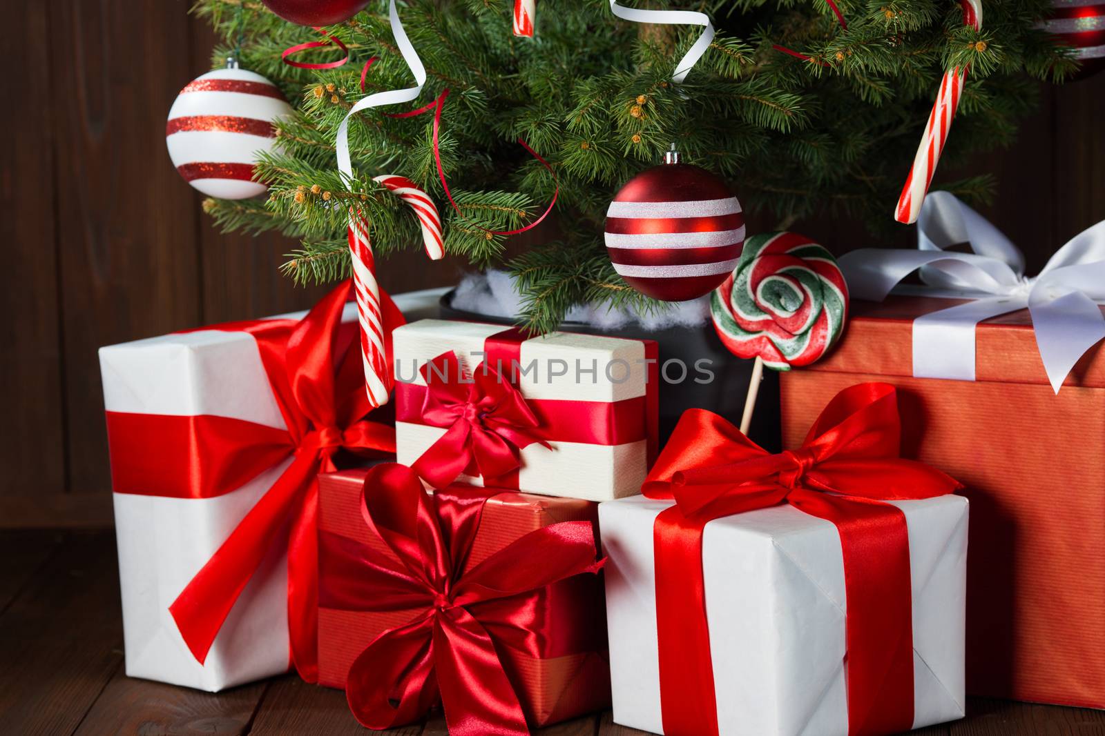 Decorated Christmas tree with gift boxes on wooden background