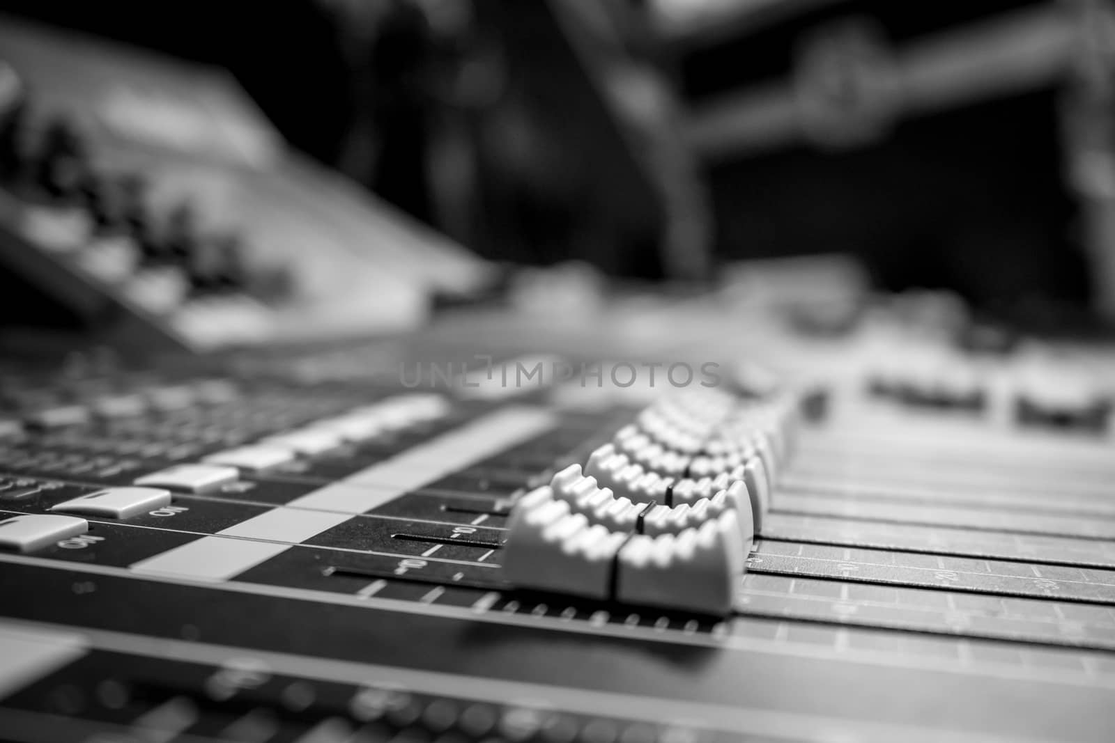 Low level view of a professional audio mixing console with rack equipment in the background