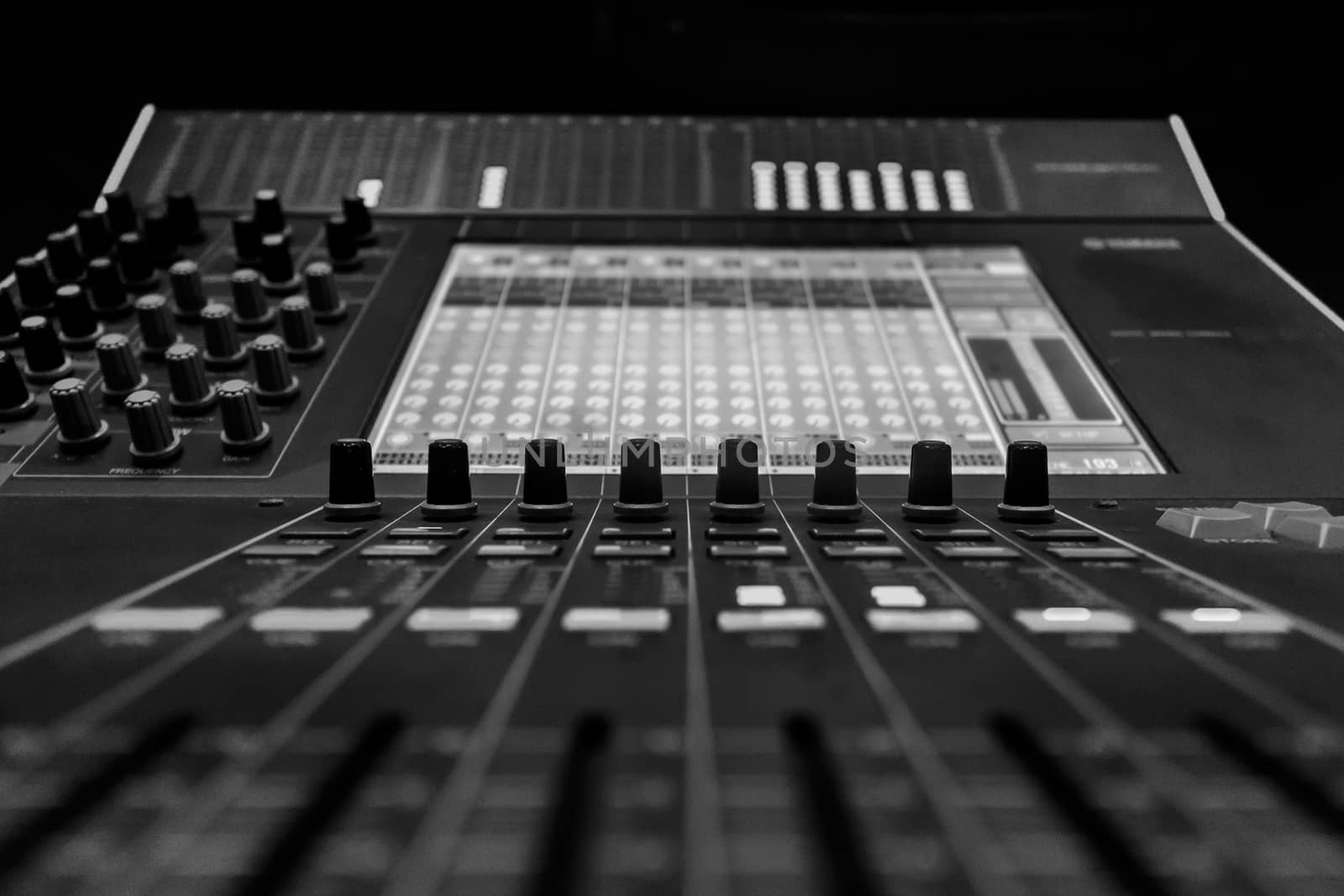 Closeup of Pro Audio Digital Mixing Console. Black control Console with digital dislpay in background