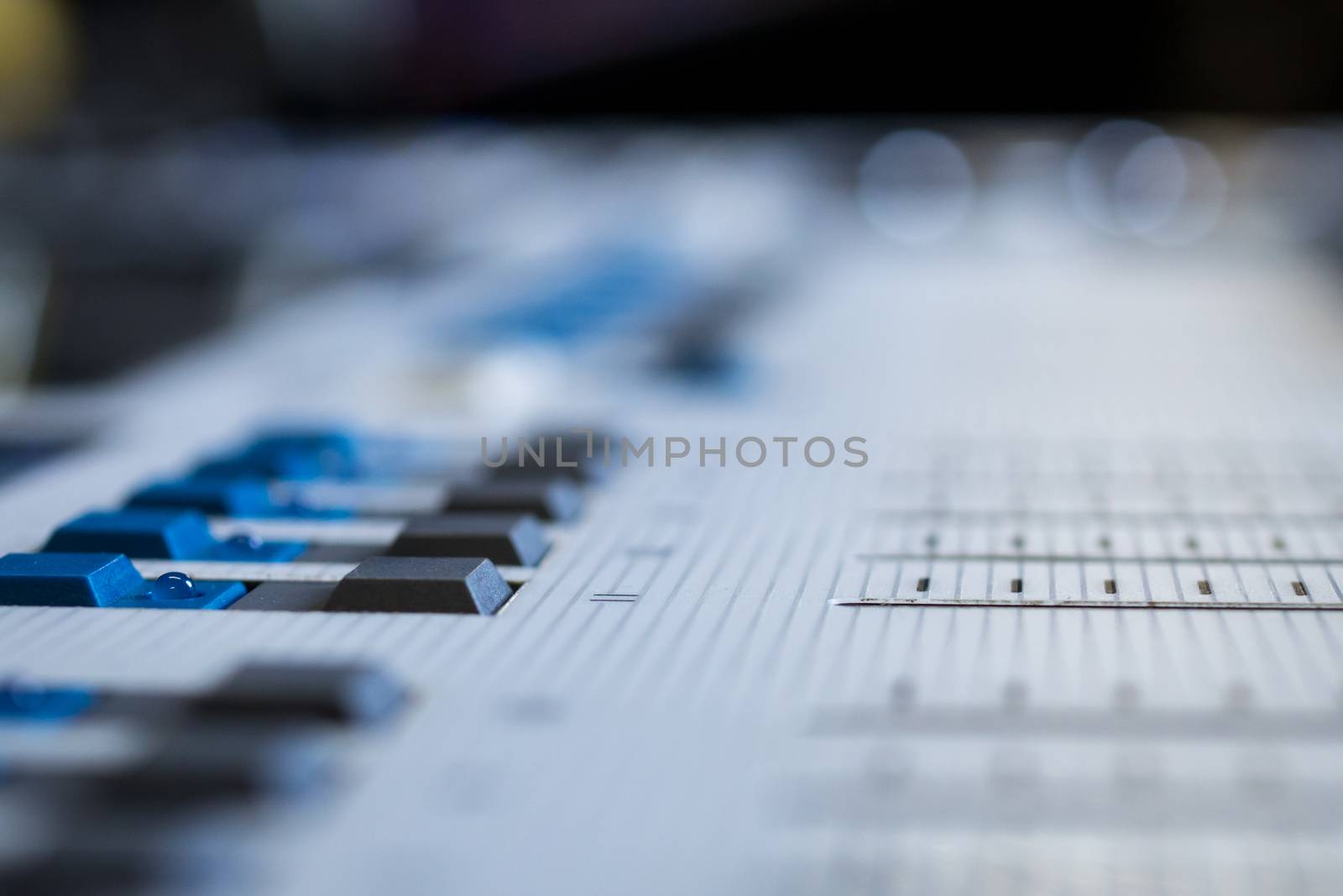 Low level view of a professional audio mixing console with soft focus background
