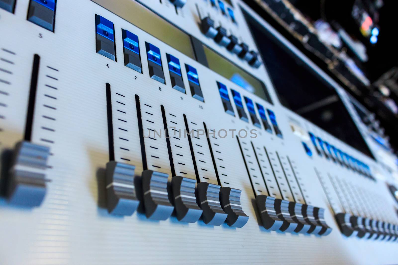 Closeup low view of Professional Lighting Designers Programming Console, blue led buttons on white desk, board