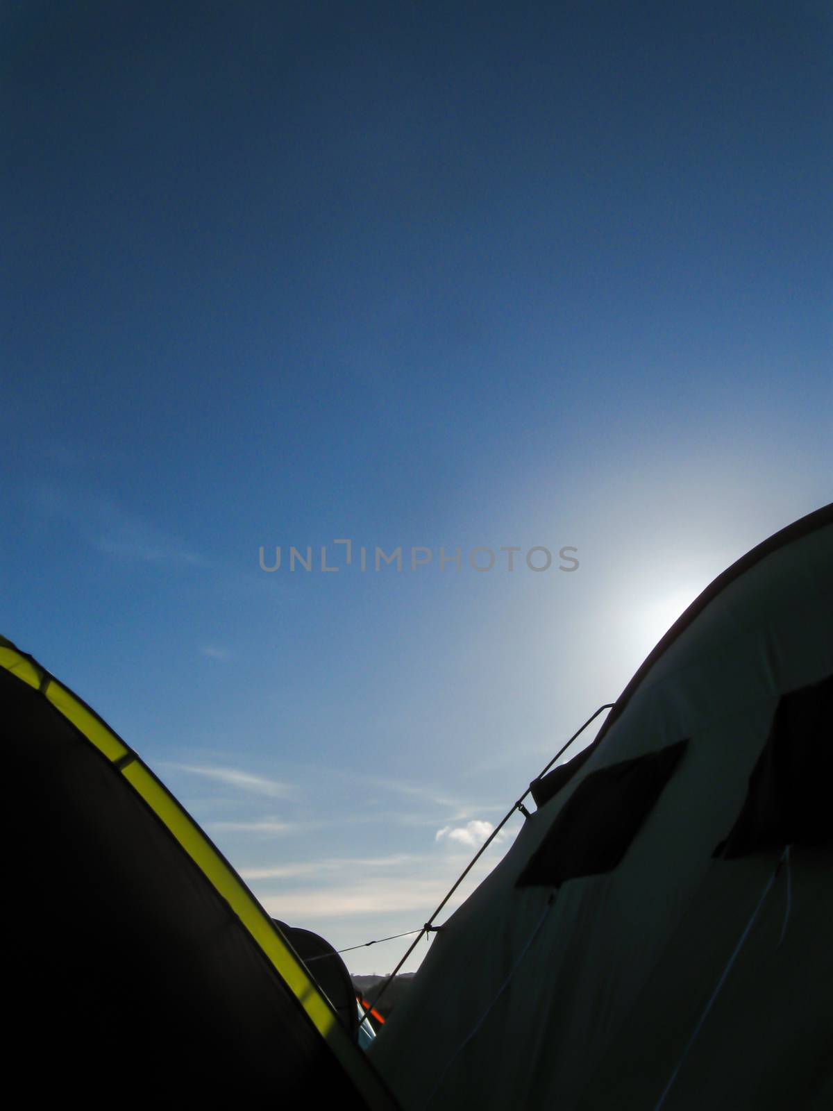 Several multi coloured tents at a festival near sunset with a rich blue sky and soft clouds