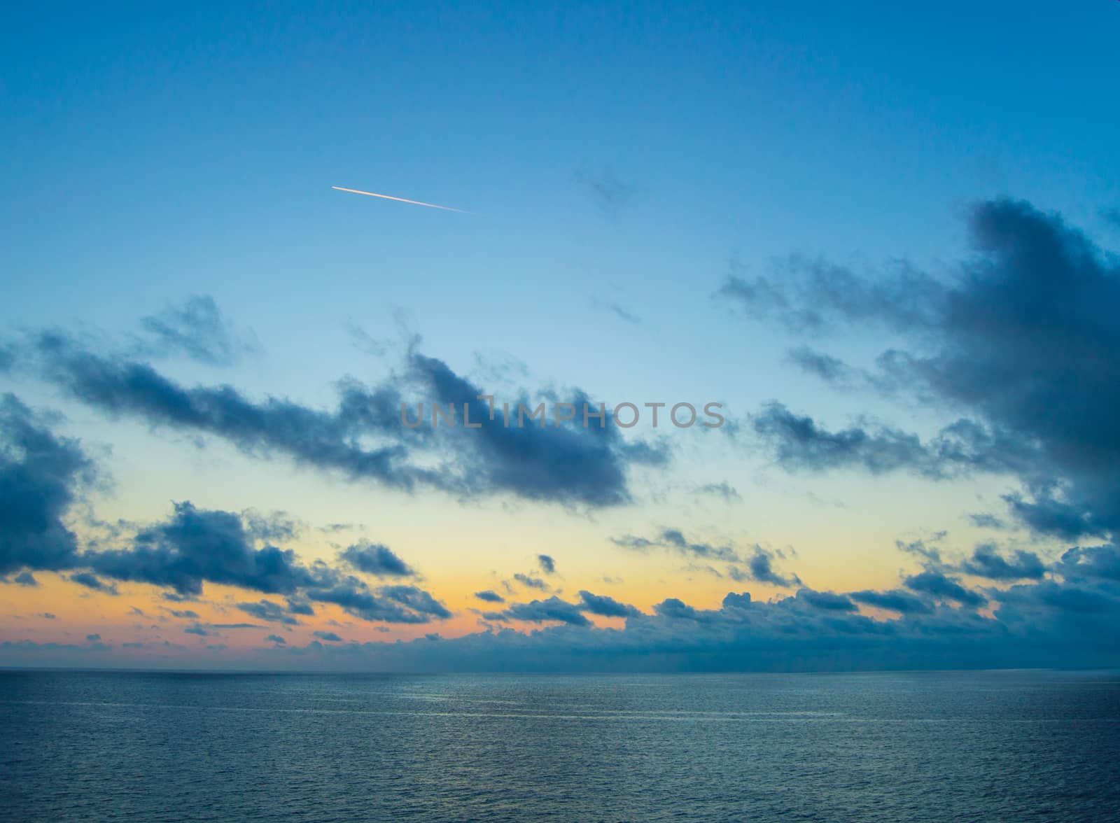 The trail of a jet over the sea on the background of a beautiful Golden sunset by claire_lucia