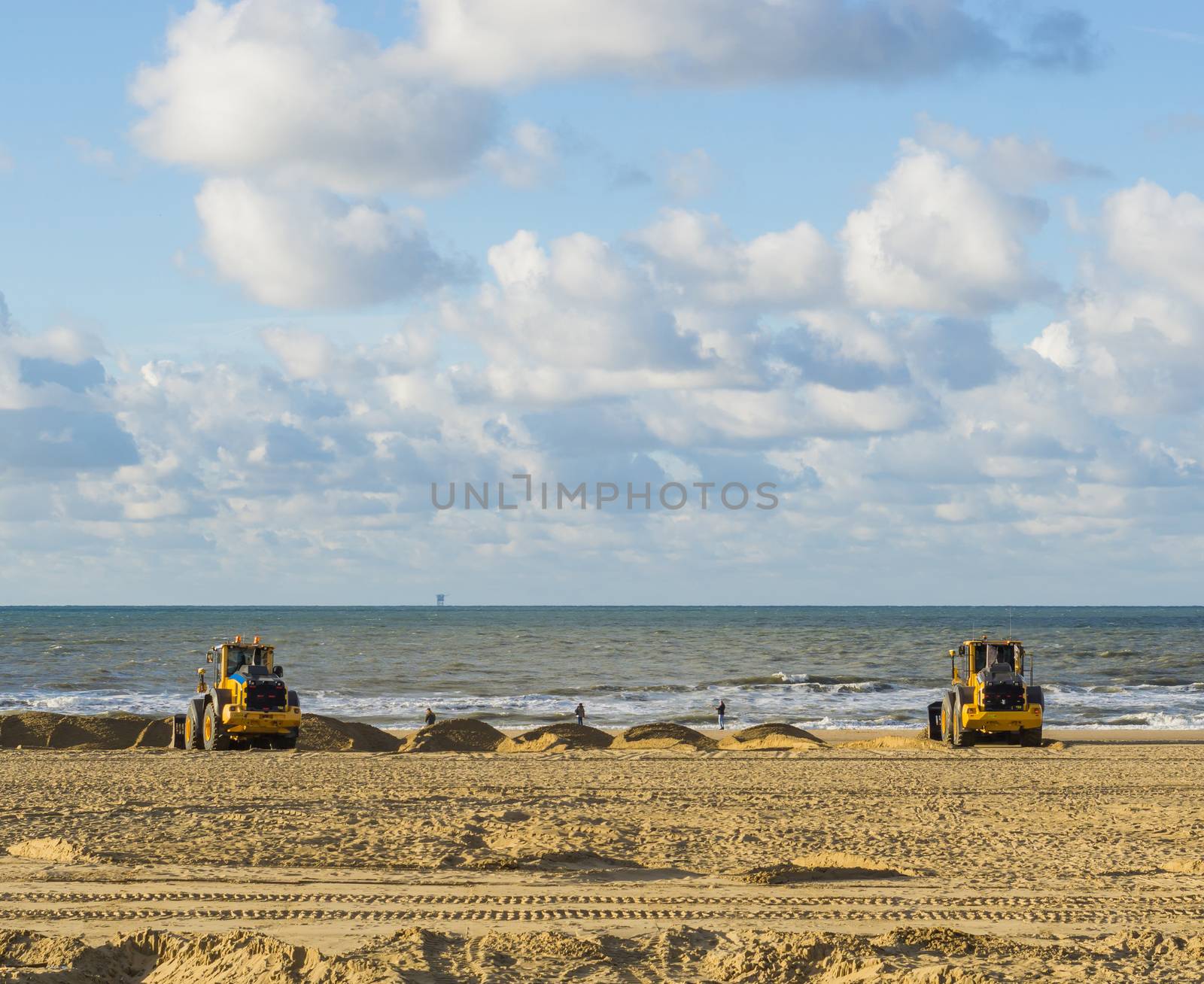 earth movers working in their equipment machines at the beach for maintenance moving the sand by charlottebleijenberg