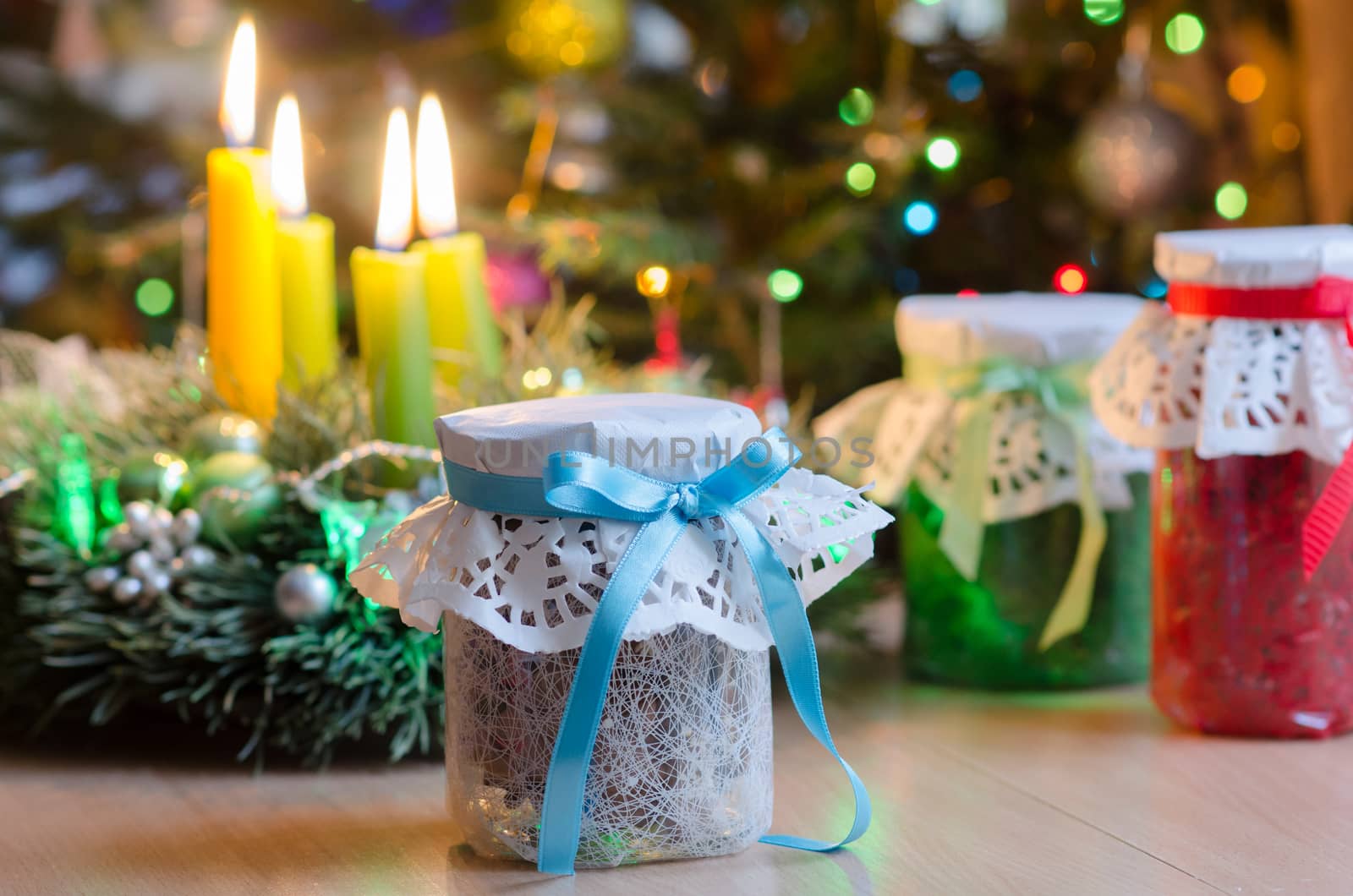 Christmas gifts on the background of branches of  Christmas candles and luminous garlands. Gifts at Christmas. Glass jars wrapped gift wrapped. In the background is lit four candles Advent wreath. 