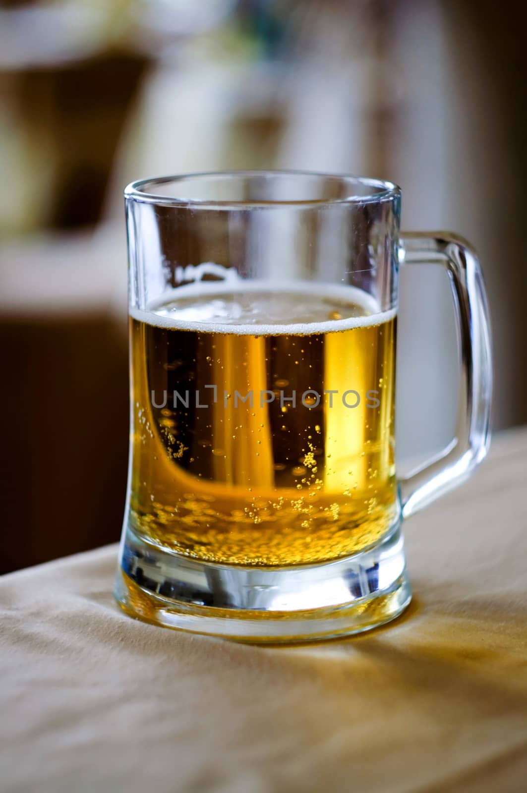 A huge glass cup of fresh beer in restaurant on the white tablecloth.