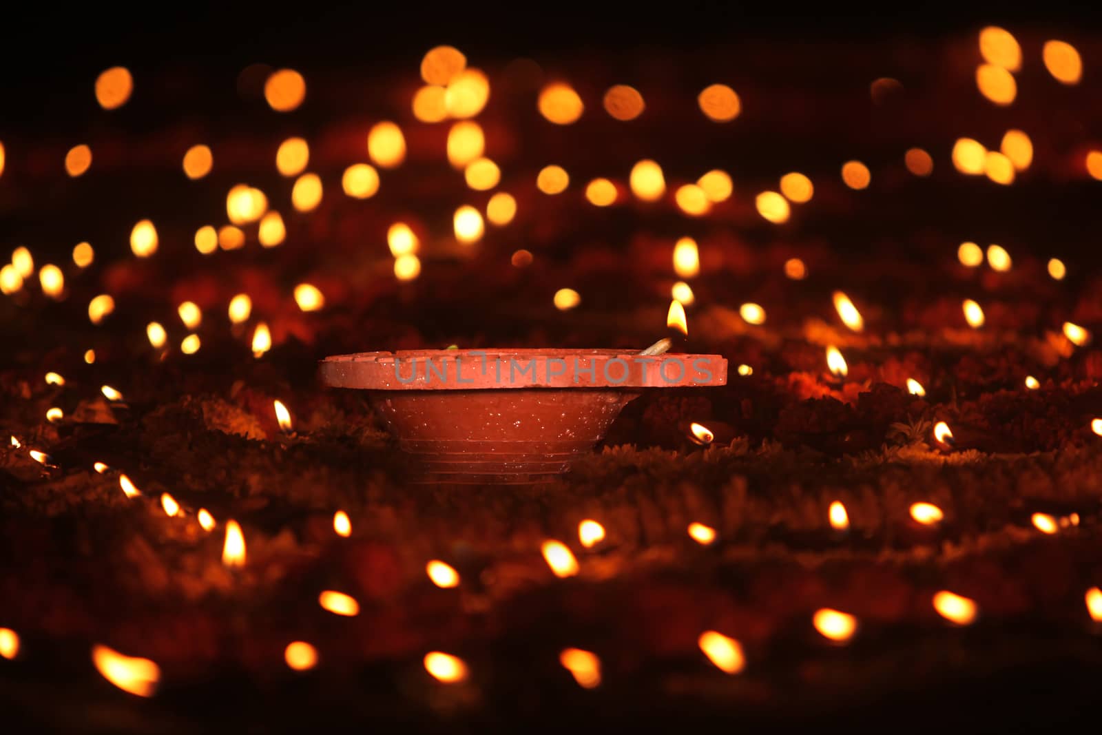 A Diwali earthen lamp kept in the center of marigold flowers and other small candles during a Hindu religious ritual, during Diwali festival in India.