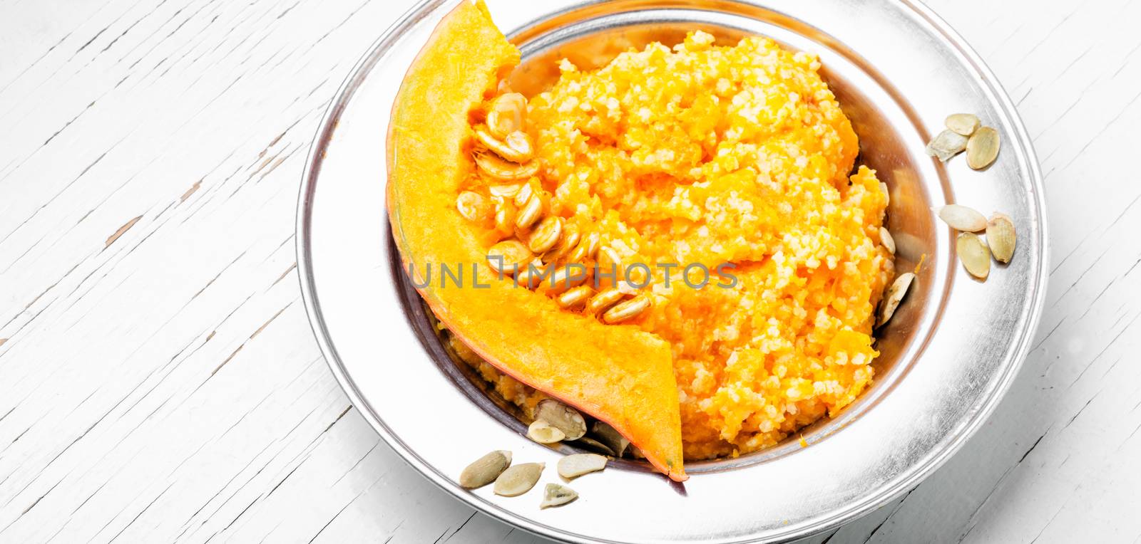 Homemade tasty porridge with orange pumpkin on white background.Healthy breakfast.