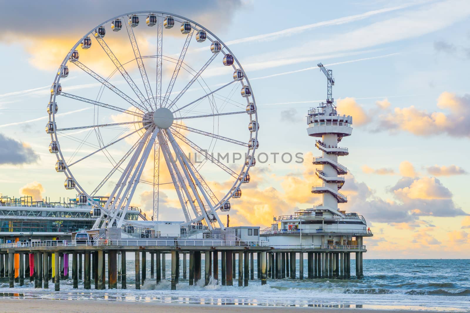 The well-known pier jetty of scheveningen beach the Netherlands with bungy jump tower and ferris wheel viewing on the ocean with waves
