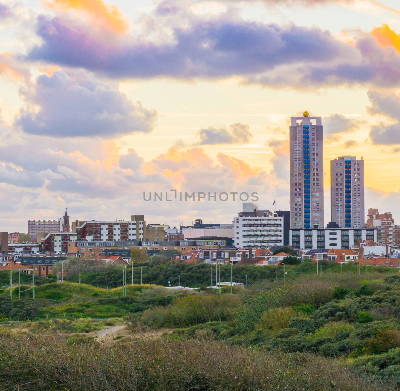 Popular and touristic location Scheveningen The netherlands a town near the beach at sunset view from the dunes on the buildings and skyscrapers by charlottebleijenberg