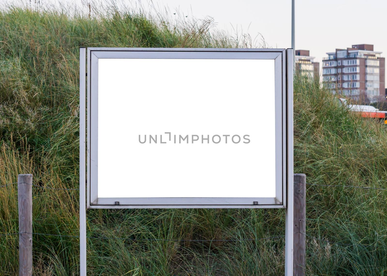 empty and blank metallic information board to put what ever you want with a green grass hill in the background by charlottebleijenberg