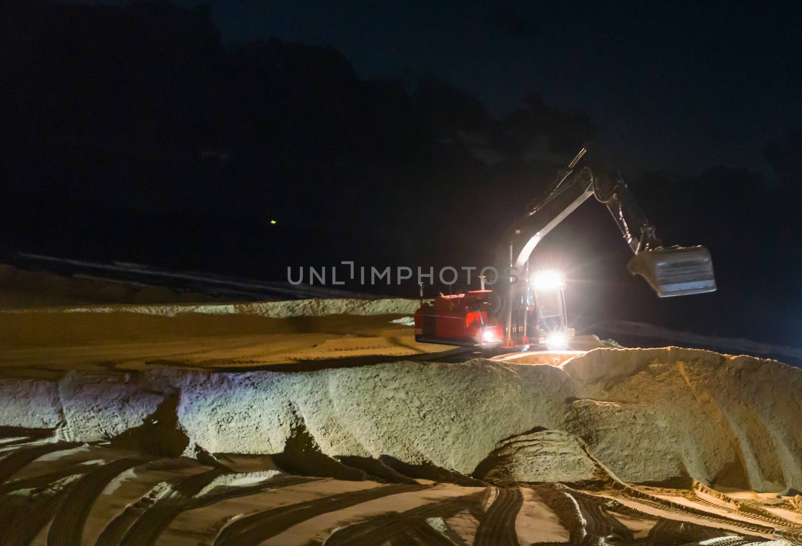 digger excavator working at night time moving the ground at the beach for maintenance