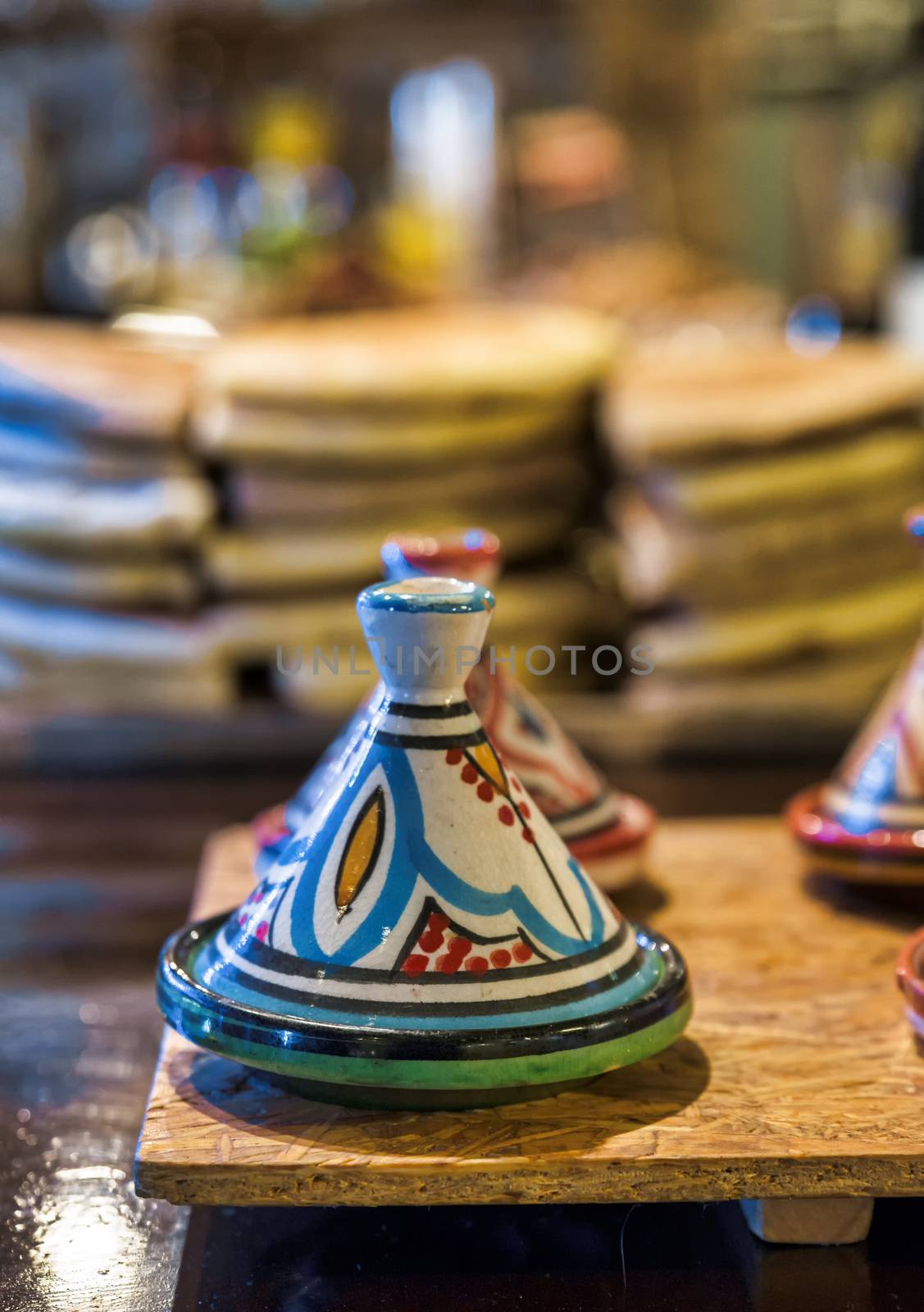 traditional tajines in a restaurant in morocco with stacked bread as background