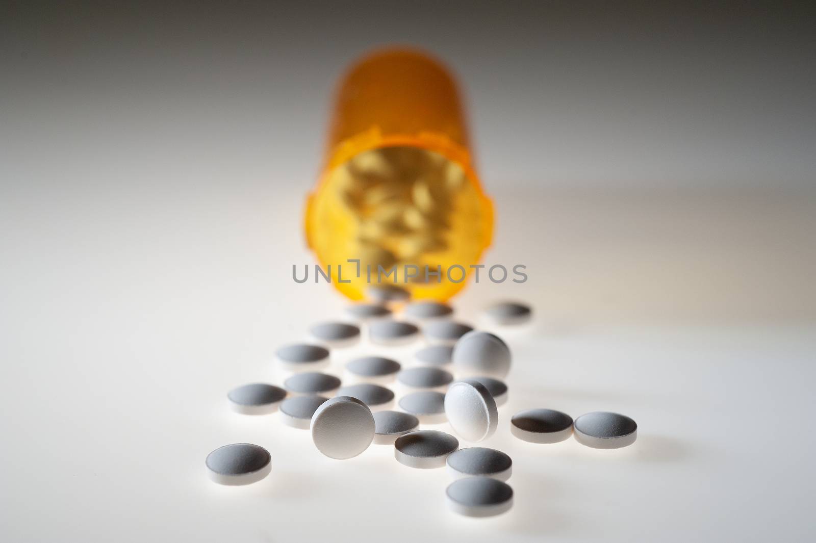 Pills or capsules of medication pouring out of an orange plastic bottle