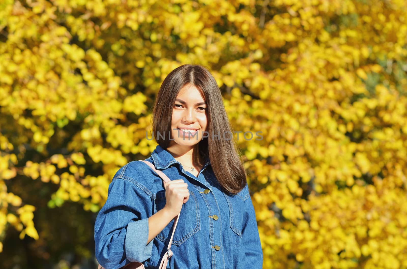 A young girl stands on a background of yellow leaves in city Park, Hiking in the fall