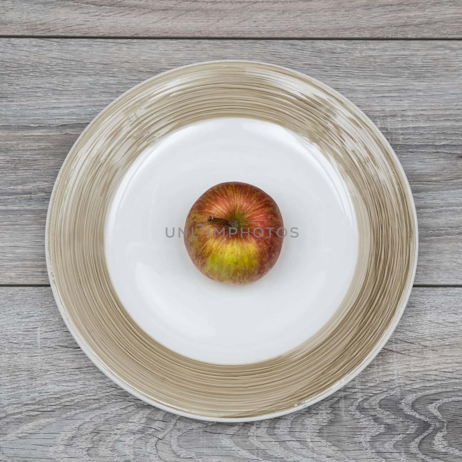 a red apple in the plate on a wooden table