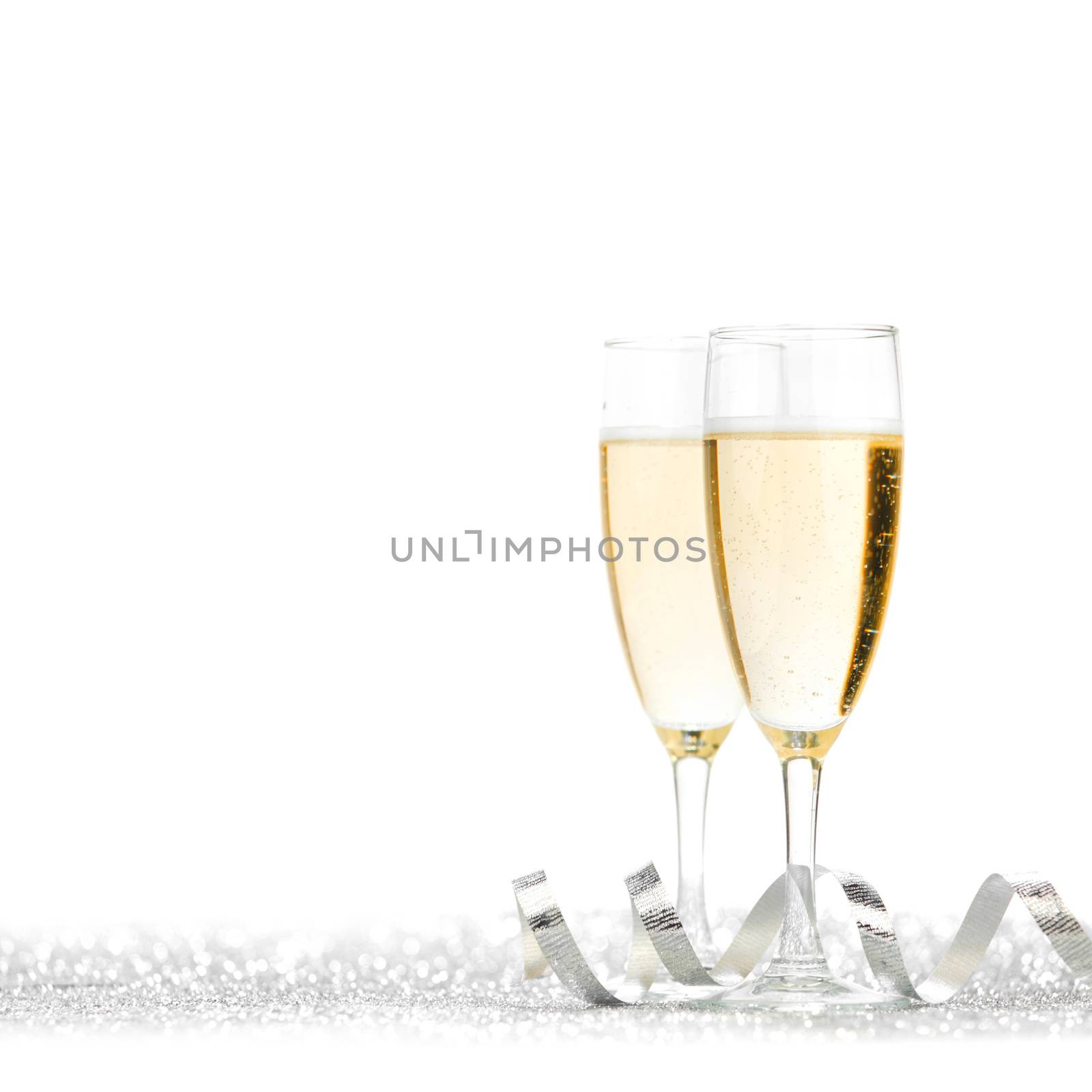 Glasses of champagne and silver ribbons on glitter background
