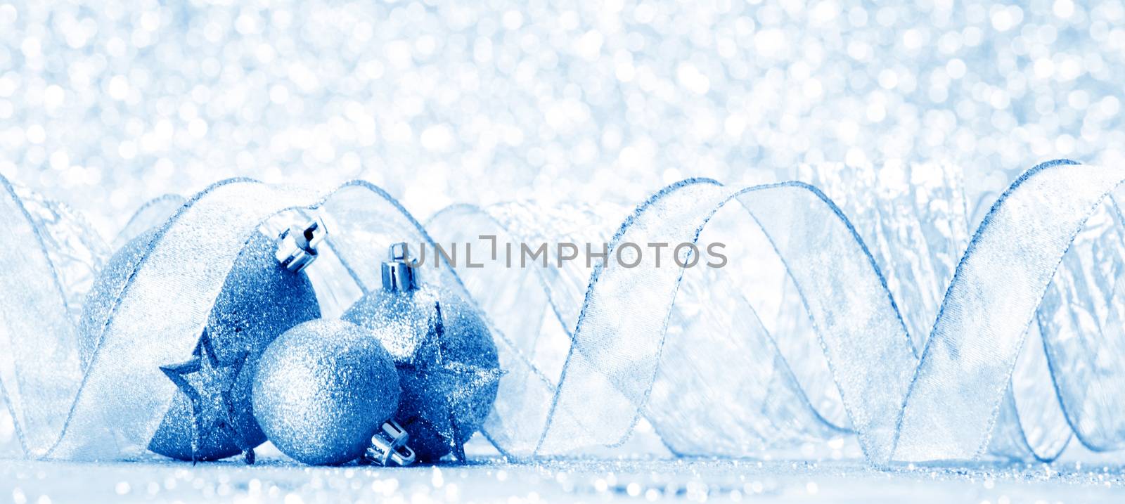 Blue Christmas balls and ribbon on abstract glitter silver background