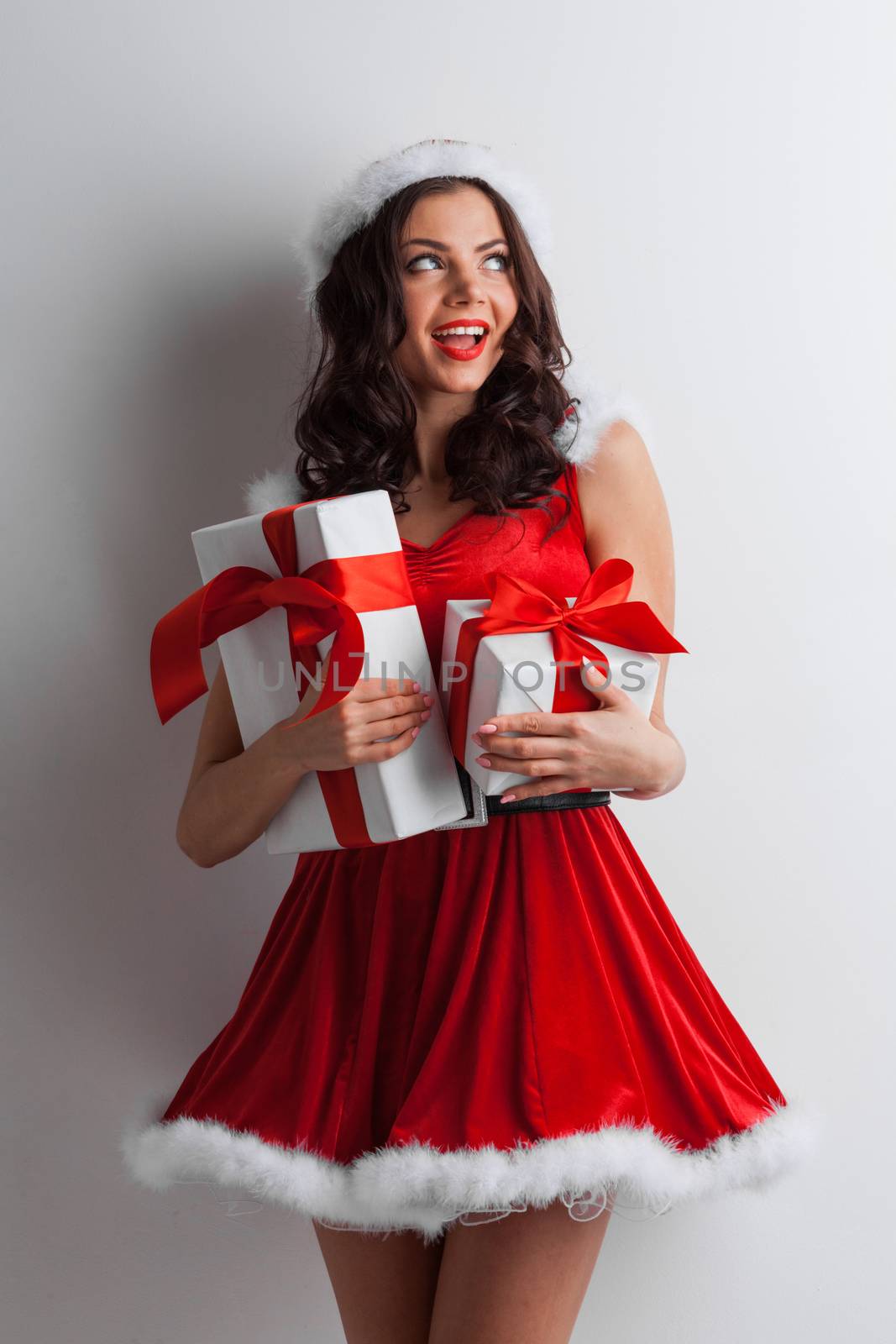 Excited surprised woman in red santa claus outfit holding Christmas presents