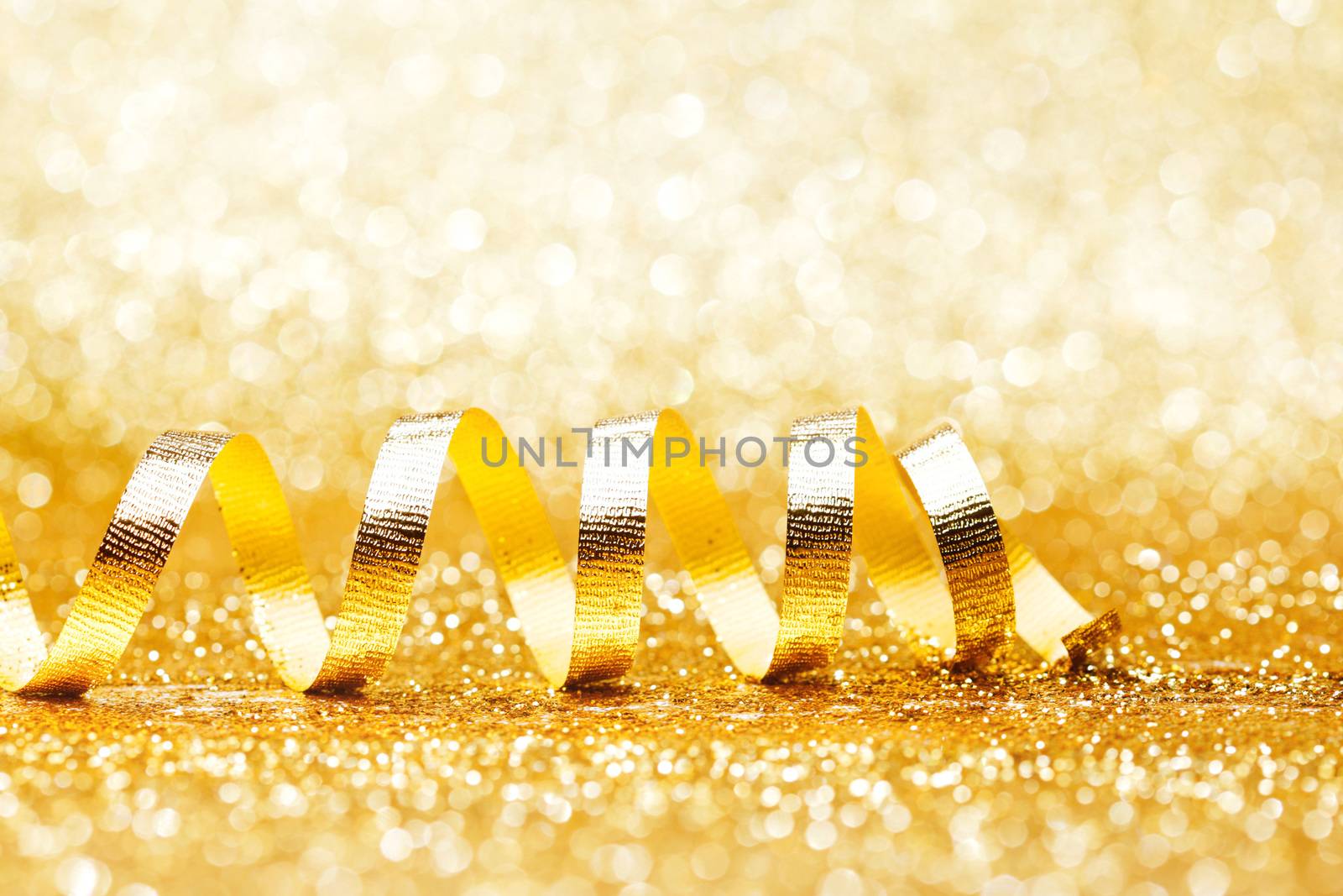 Curly golden serpentine on shiny glitter background, holiday concept