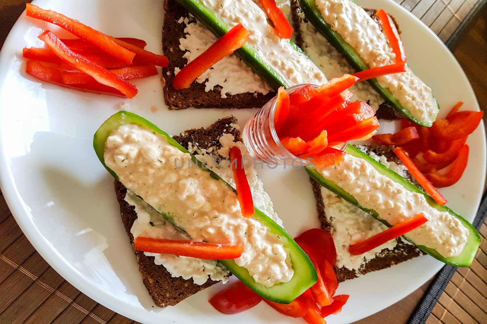 Cucumber boat with fresh quark, pepper strips on black bread     by JFsPic