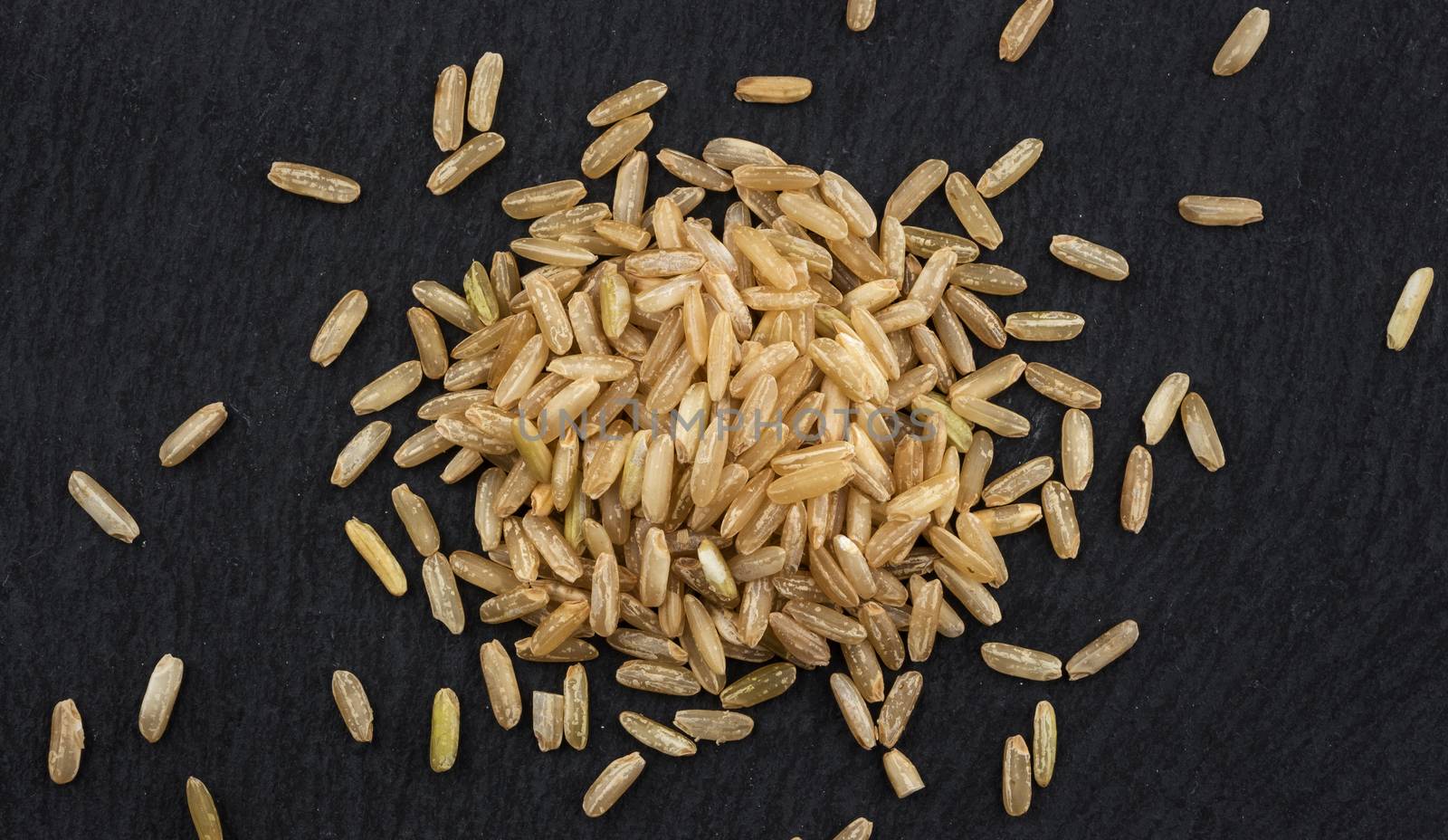 Brown rice groats on black background. Top view by xamtiw