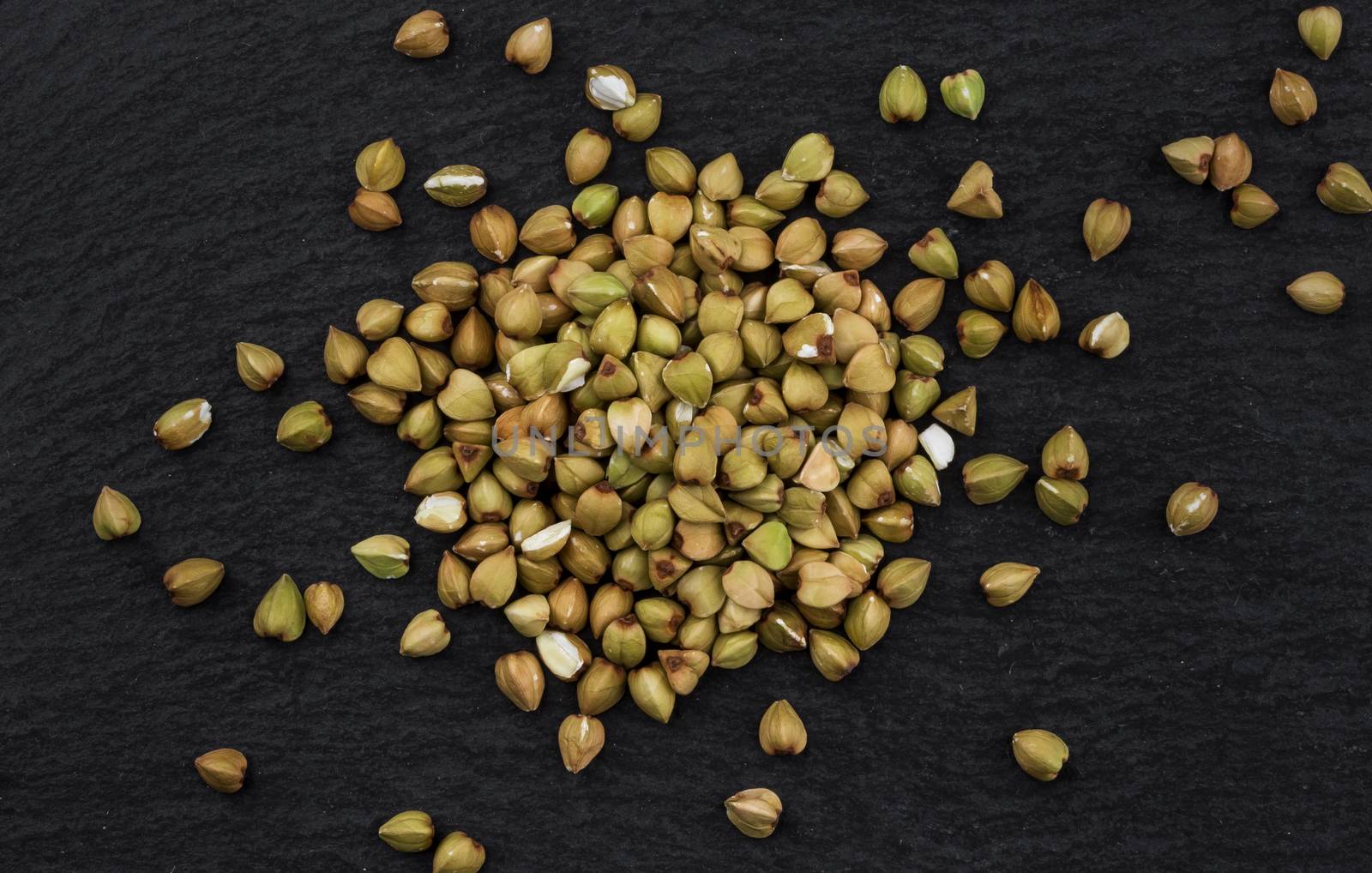 Heap of green buckwheat grains on black background, top view