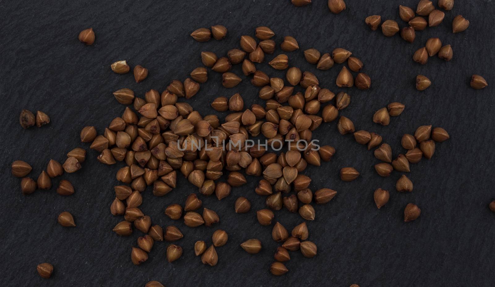 Heap of buckwheat grain on black background, top view