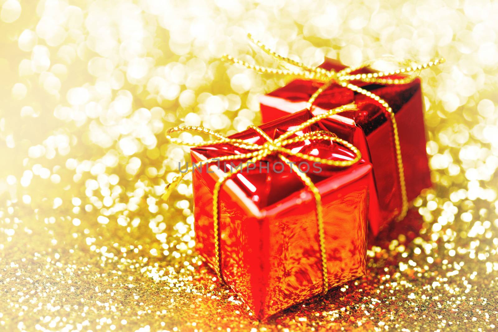 Decorative red boxes with holiday gifts on shiny glitter background
