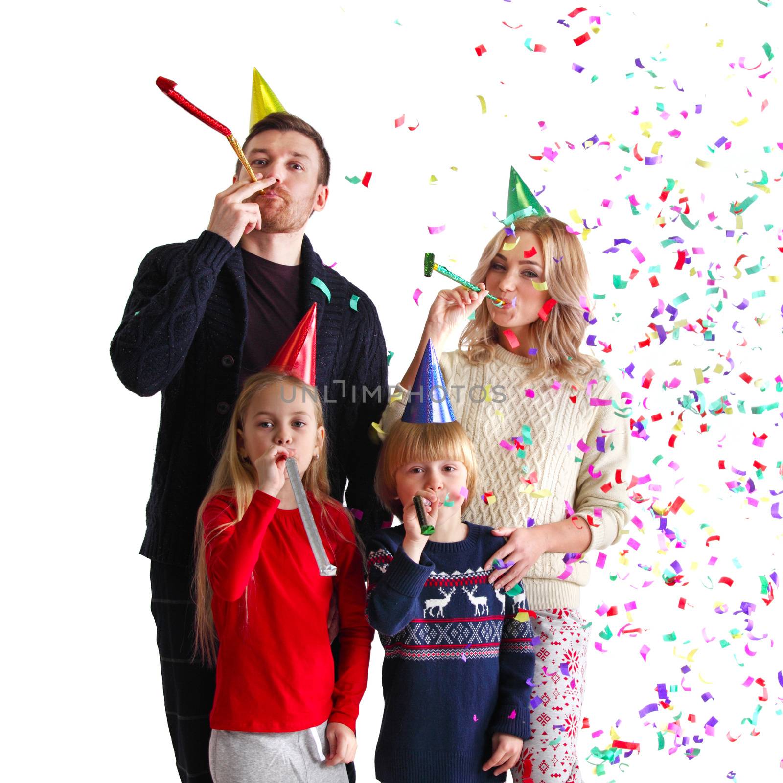 Family blowing party trumpets with confetti celebrating new year