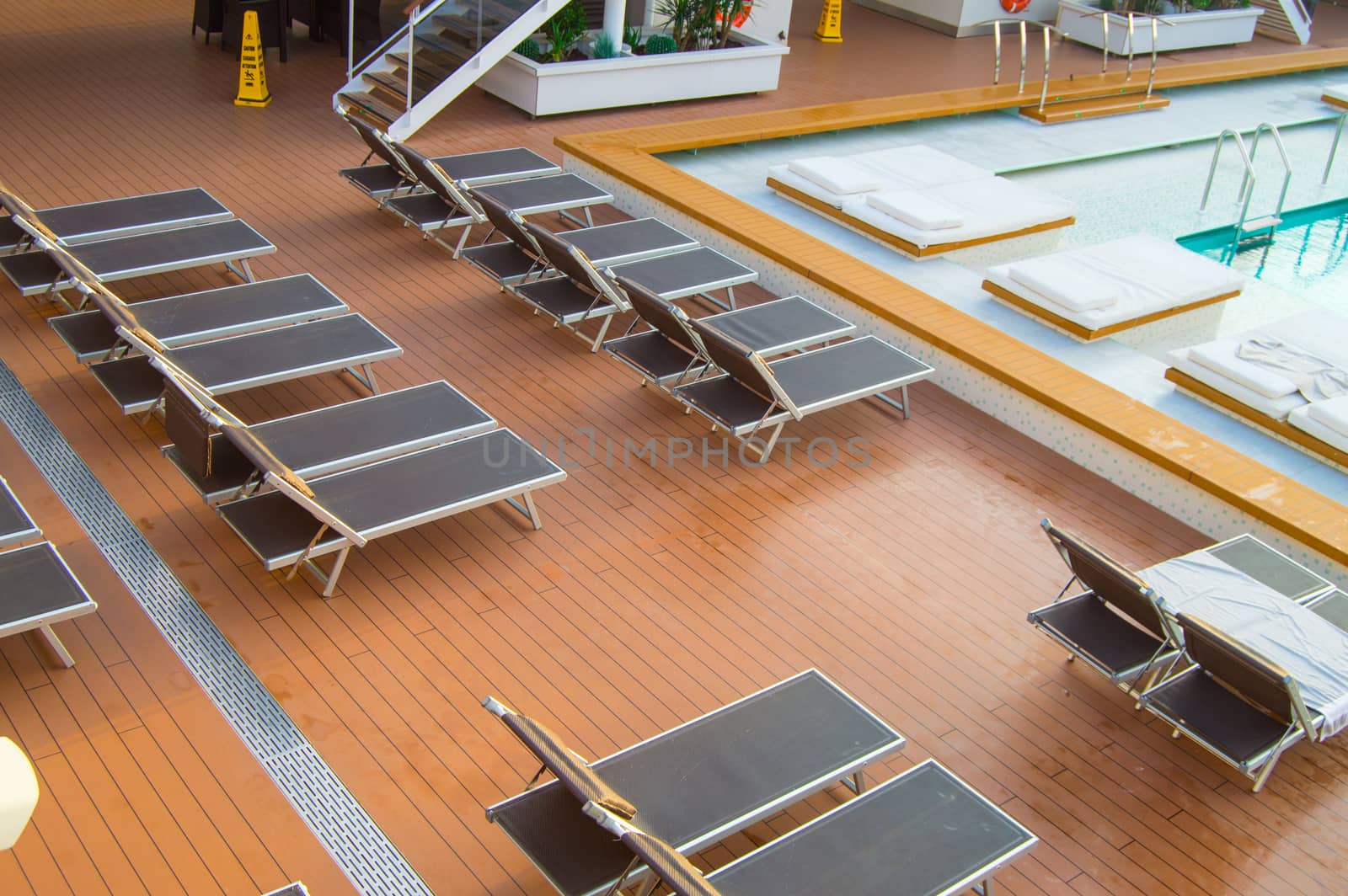 Top view of the luxurious pool with empty sun beds on the open deck of a modern cruise liner.
