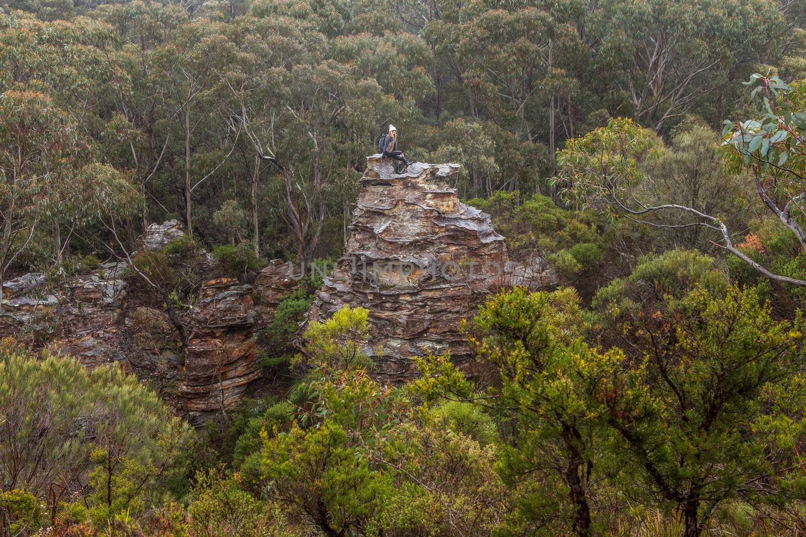 Female hiker climbs onto  natural rock pillar tower in Blue Mountains Australia