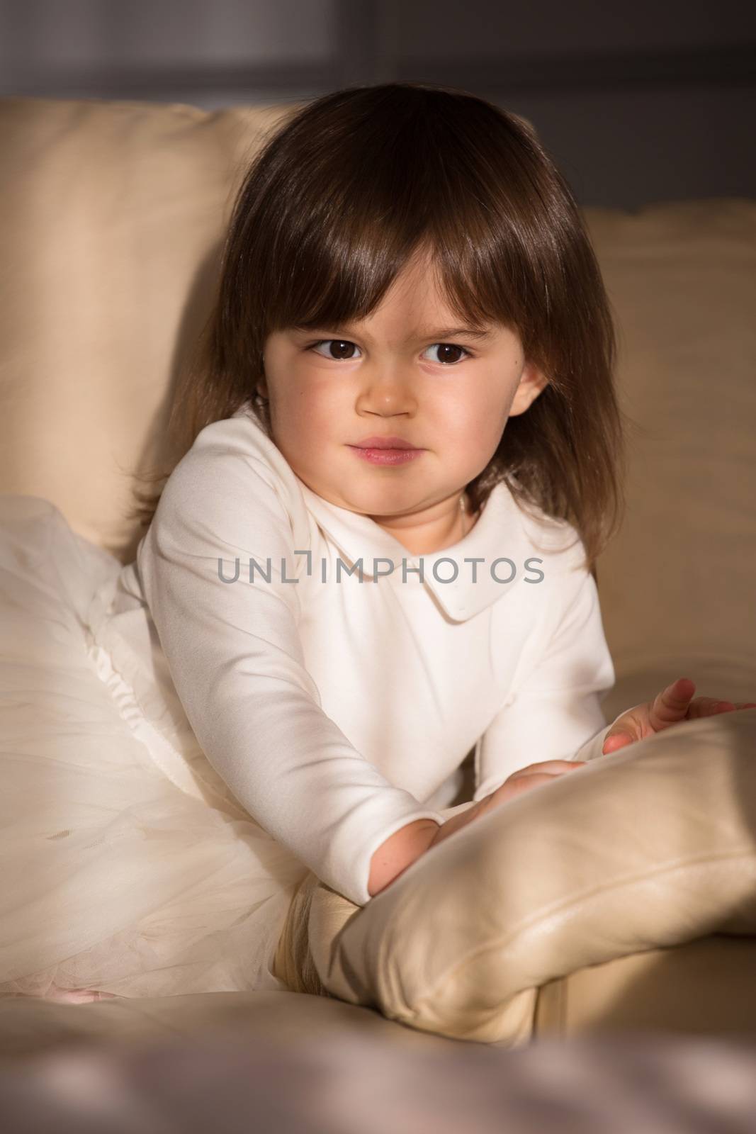 Pretty baby girl with brown hair in white dress