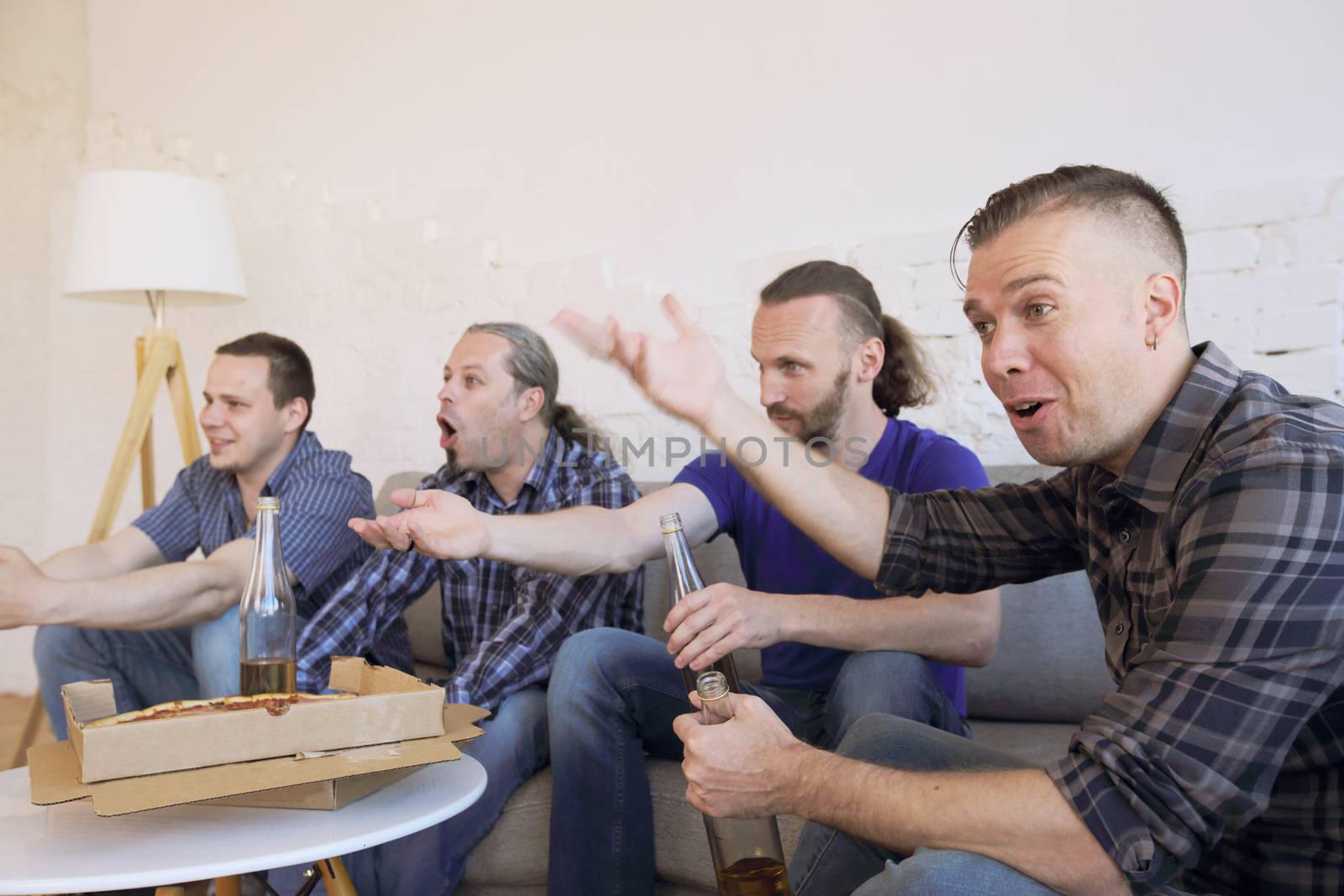 Male friends sports fans watching loosing football match on TV at home on couch sharing snacks drinking beer