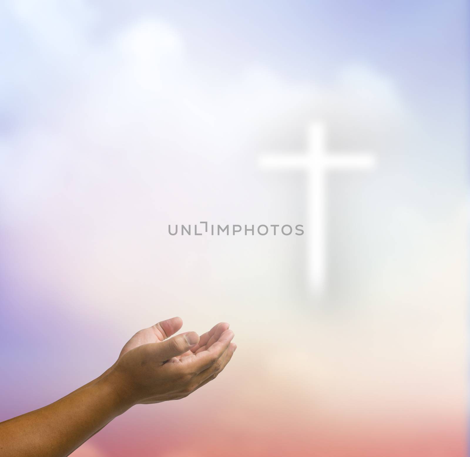 open hands praying the cross on blur sky background.