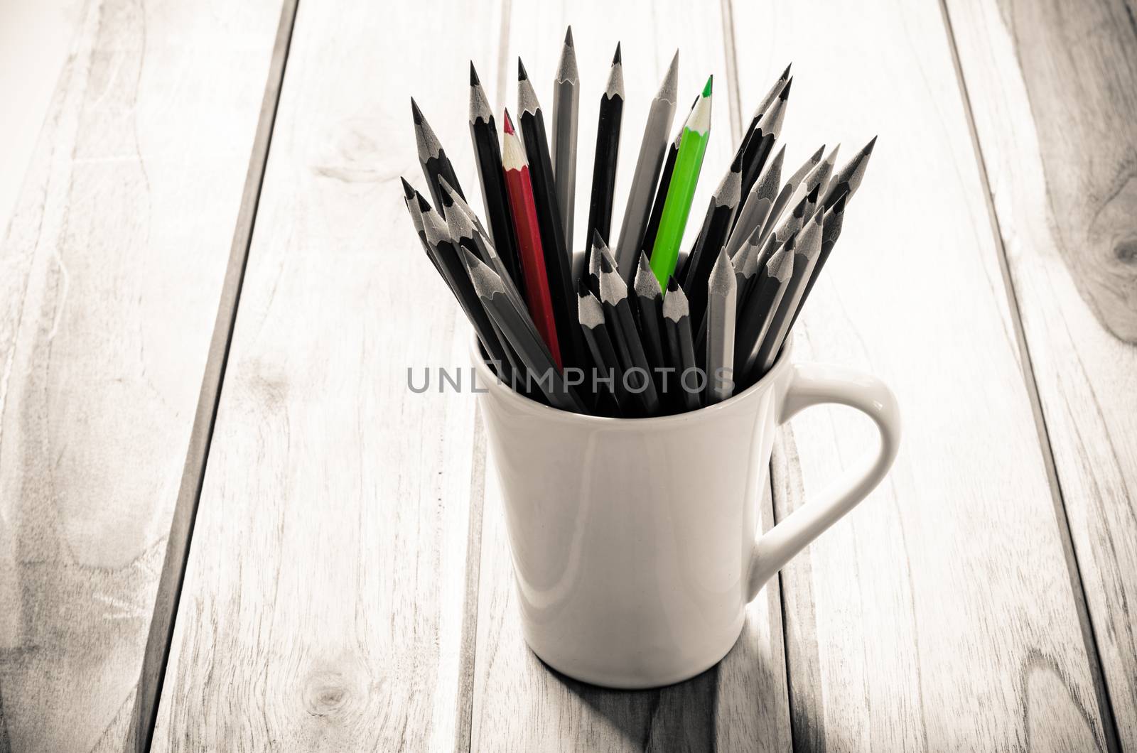 Stack of pencils in a glass on wooden background,tone sepia by photobyphotoboy