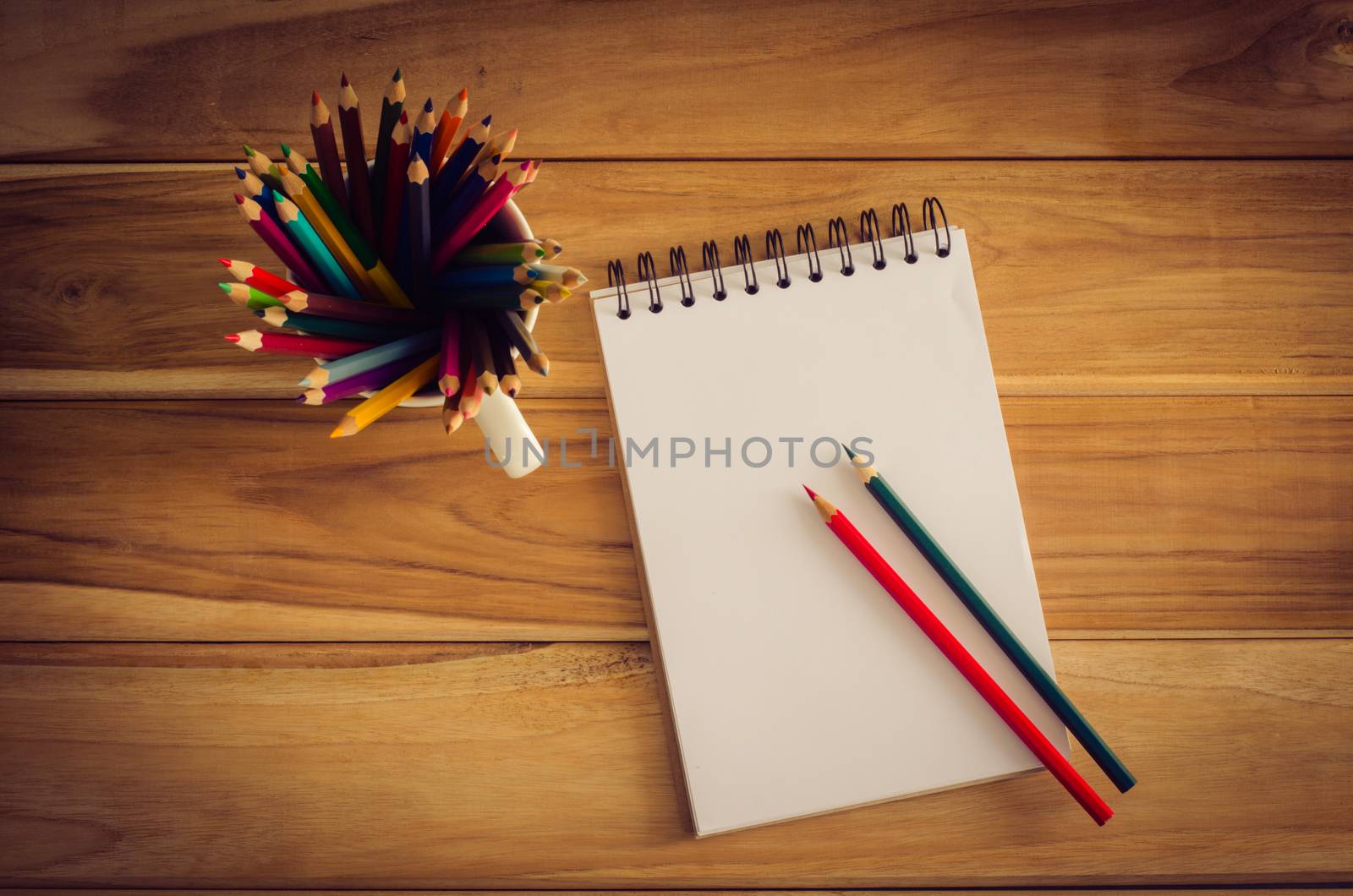 Color pencil and sketchbook on wood table by photobyphotoboy