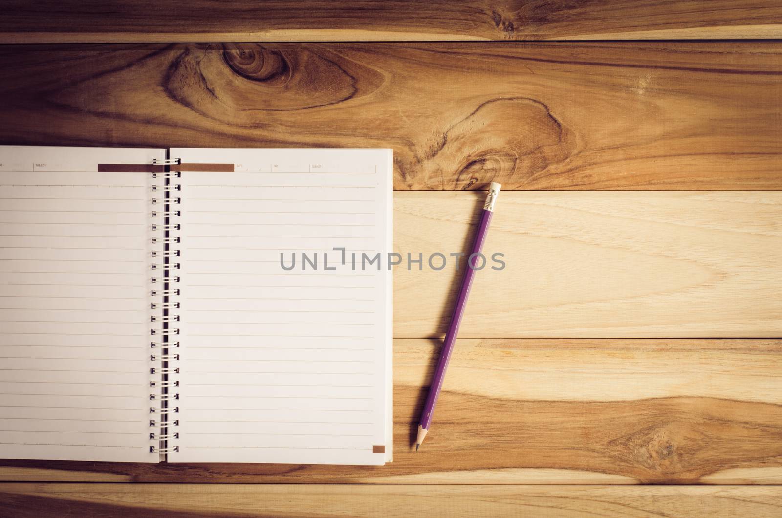 Color pencils in the cups and notebook placed on a desk. by photobyphotoboy