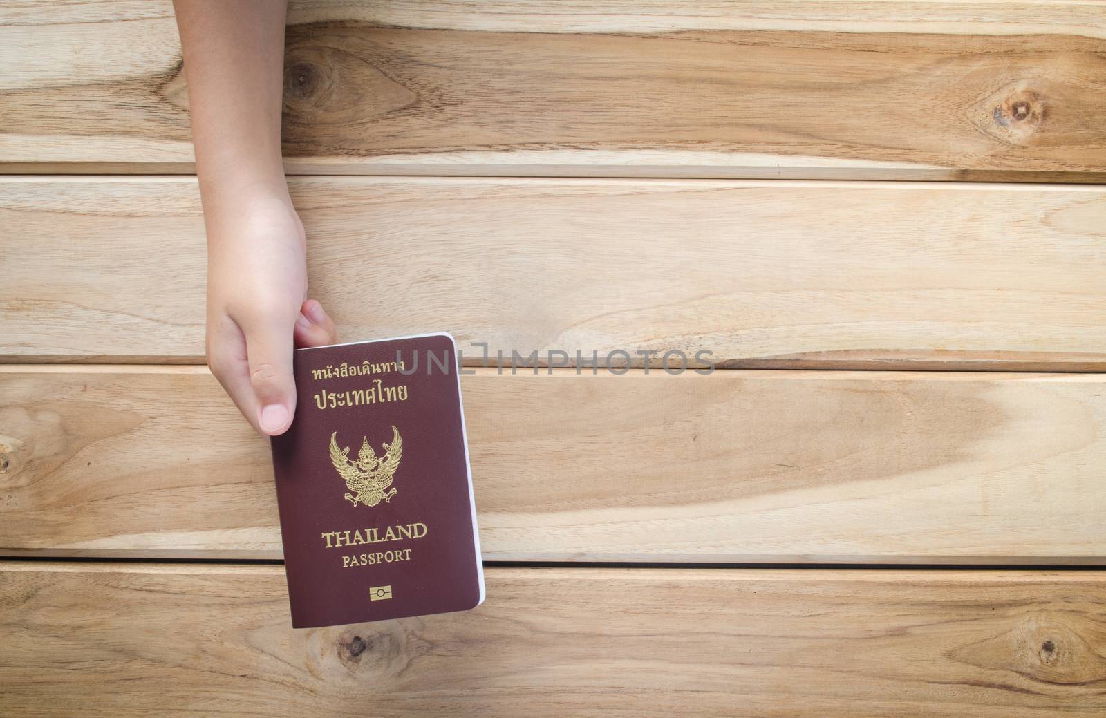 hand holding a thailand Passport on wooden background