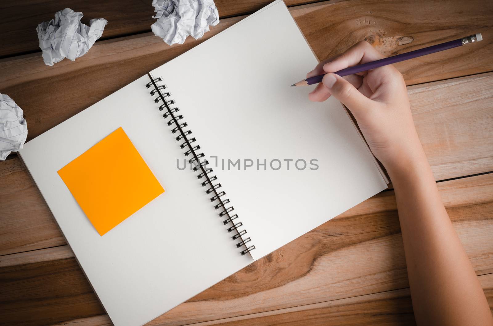 Hand-written note in pencil on a wooden table - hand focus by photobyphotoboy