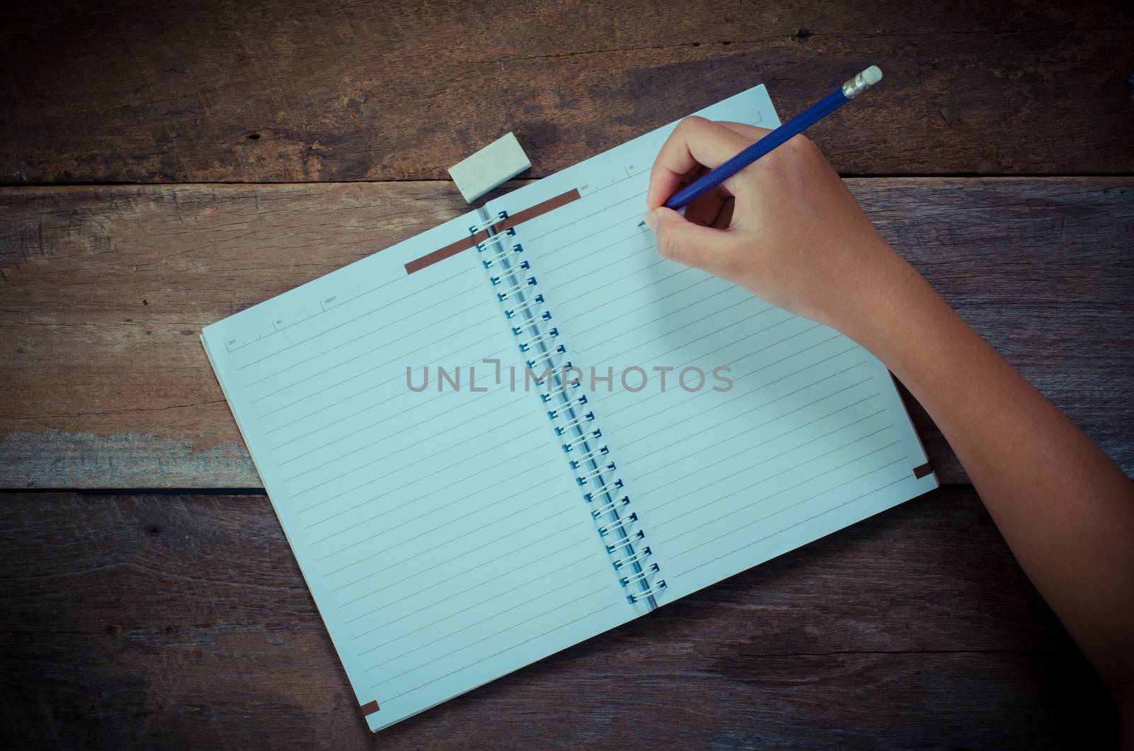 Hand writing in open notebook on table